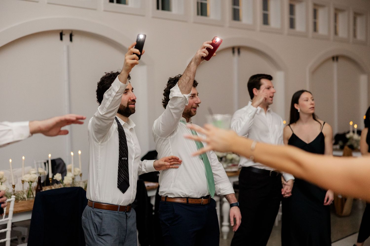 Wedding reception guests raising drinks in celebration during a party dance moment.
