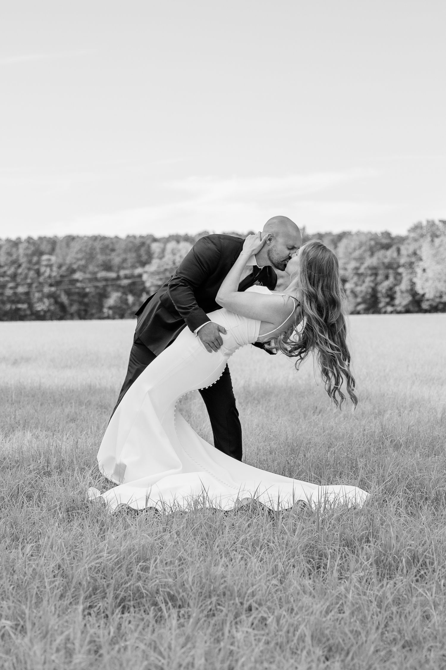 Romantic black and white portraits of a couple in a serene field.