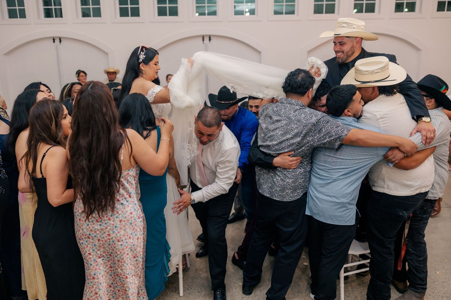 Wedding guests form a circle on the dance floor during a lively reception celebration.