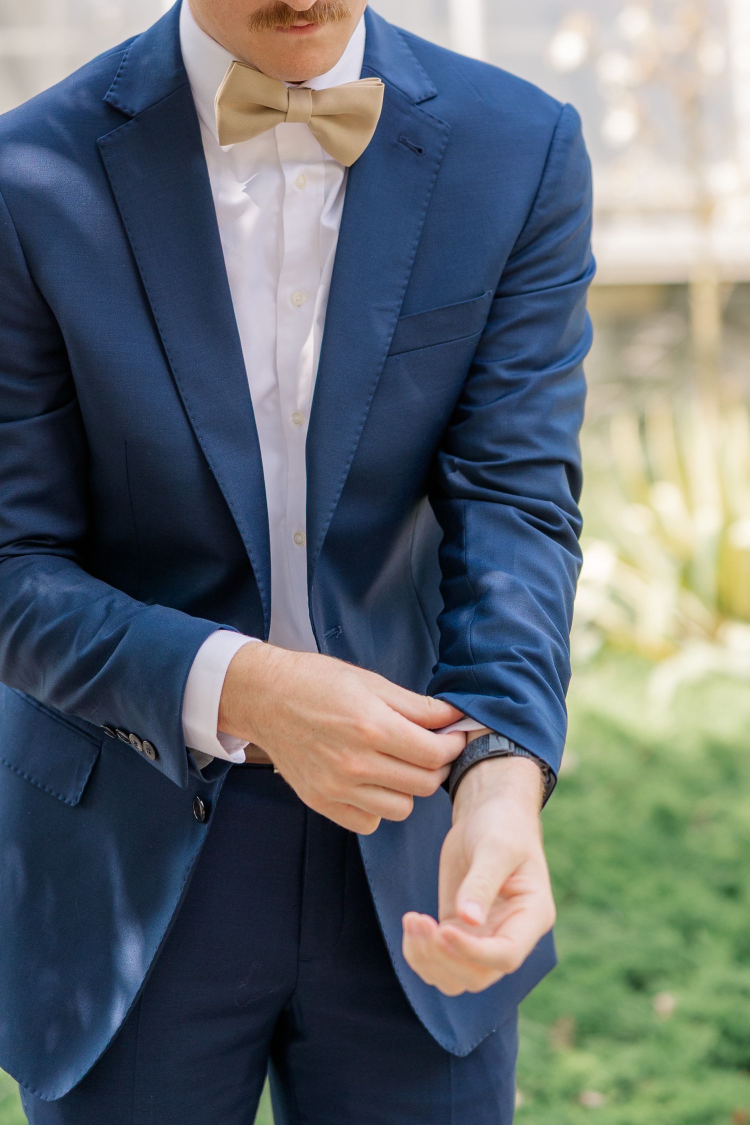 Close-up of navy blue suit jacket with white dress shirt being adjusted.