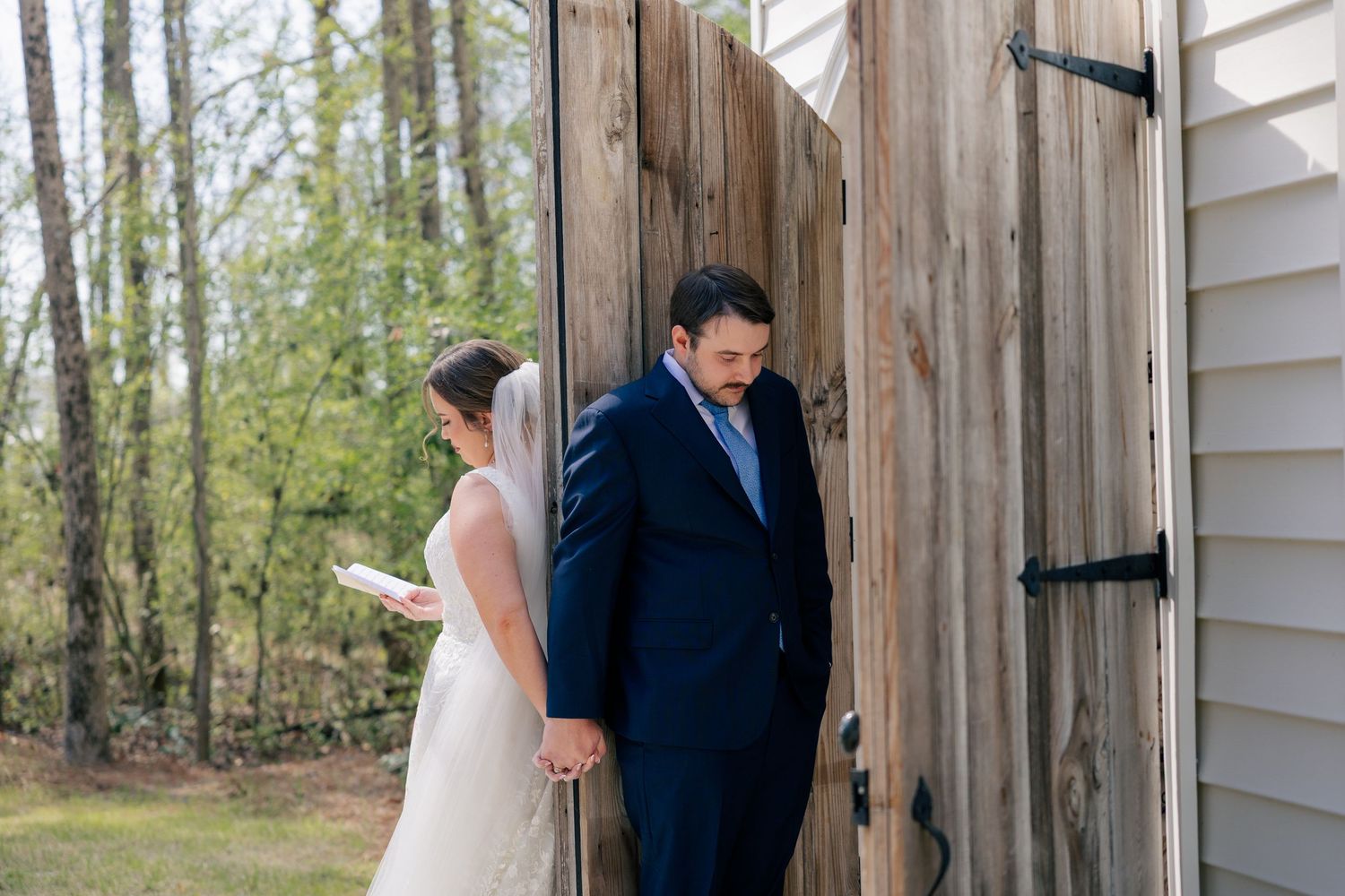 A couple shares an intimate moment near rustic wooden doors outdoors.