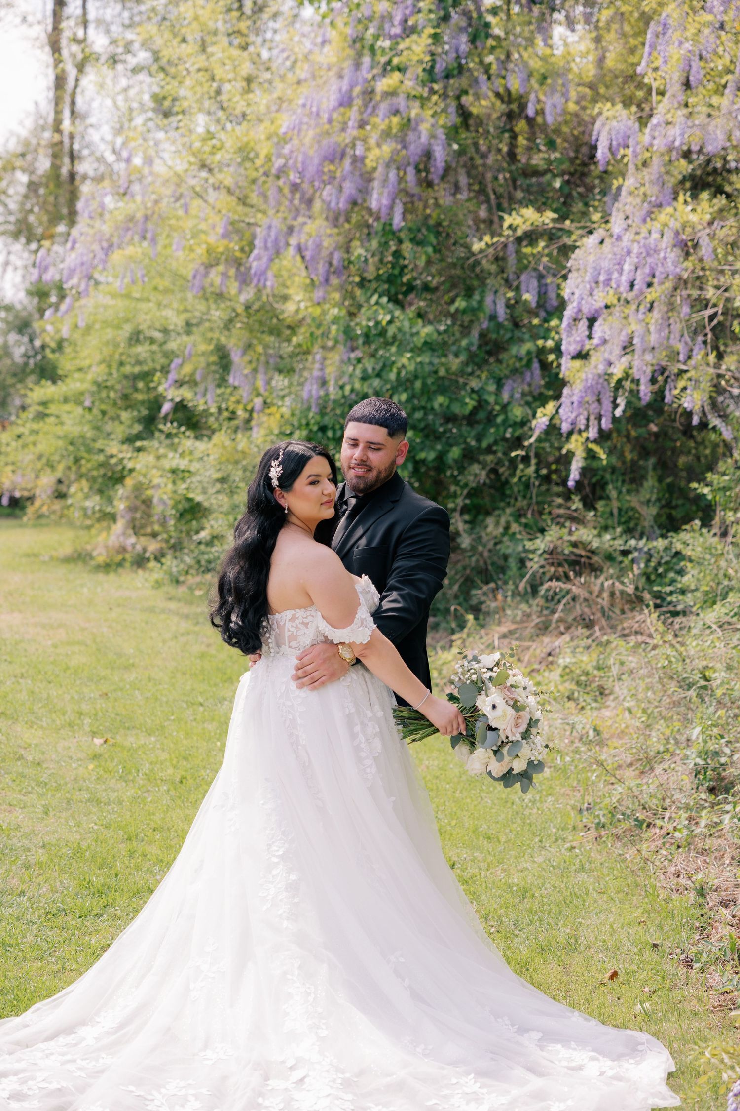 Romantic wedding portrait with cascading wisteria and a stunning white lace gown with long train.