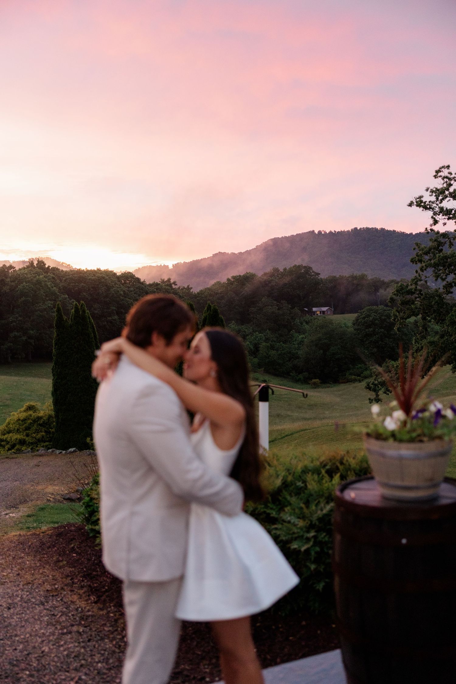 A romantic sunset embrace with mountains and pink sky in the background.