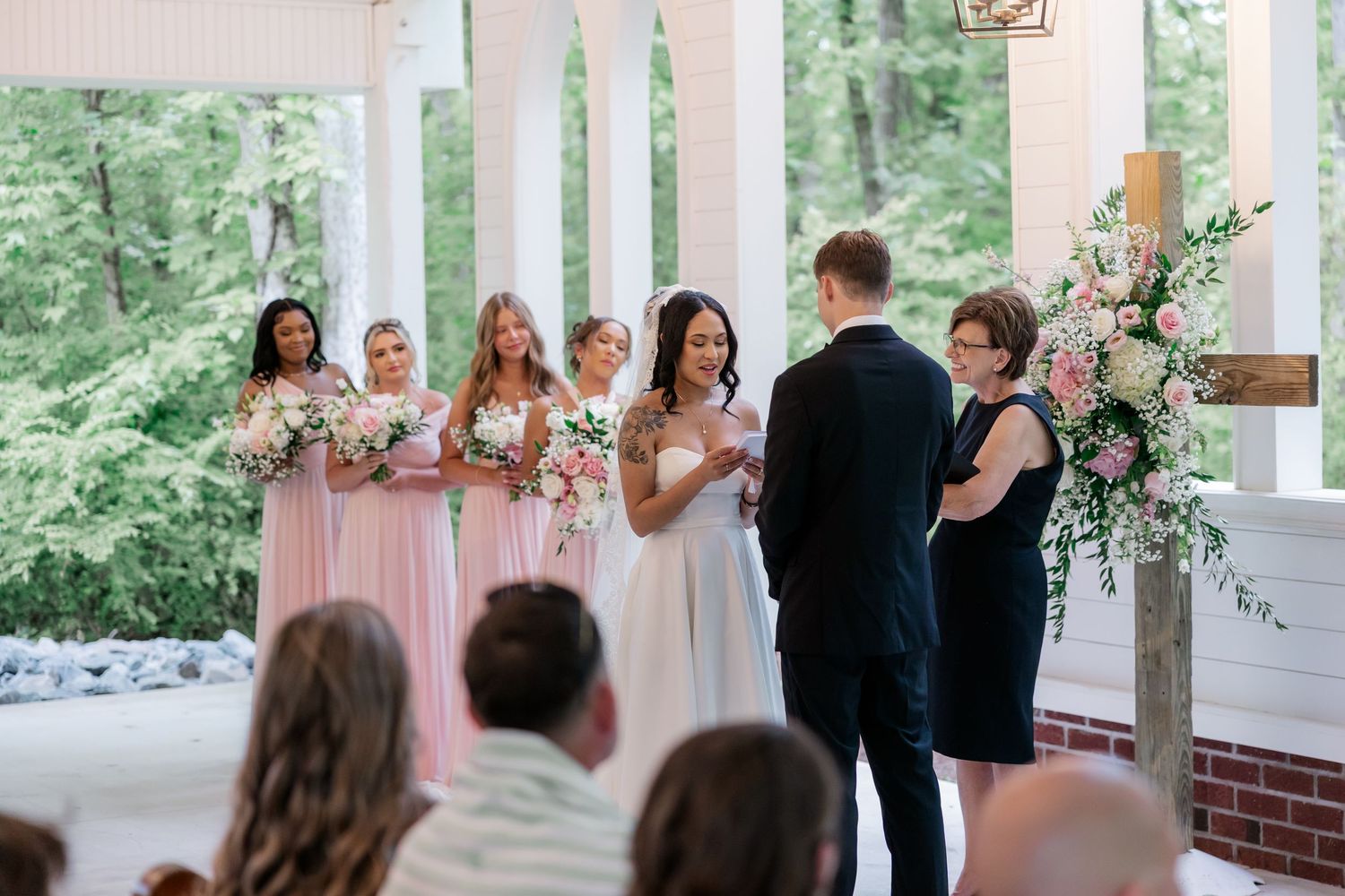Wedding ceremony taking place on a covered outdoor porch with white pillars.
