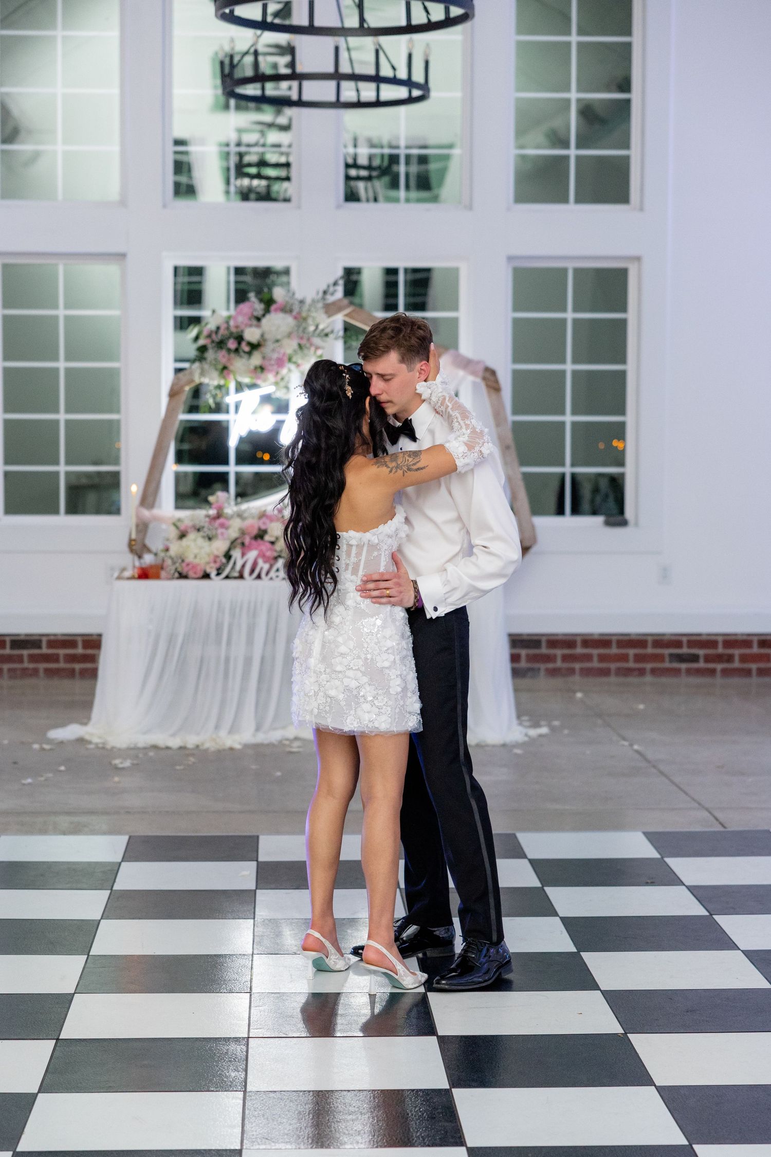 Couple shares an intimate dance moment on a black and white checkered floor at their wedding reception.