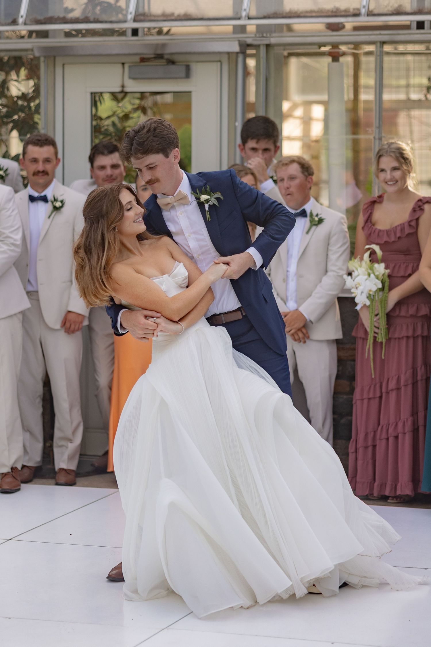 Wedding couple sharing an intimate dance moment surrounded by their wedding party.