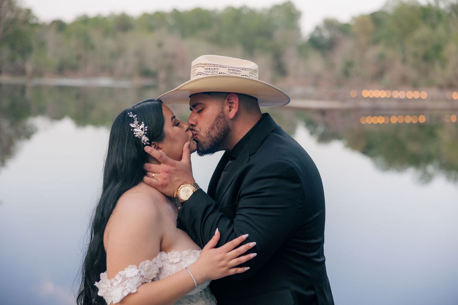 Romantic couple shares intimate moment by lakeside during sunset wedding photos.