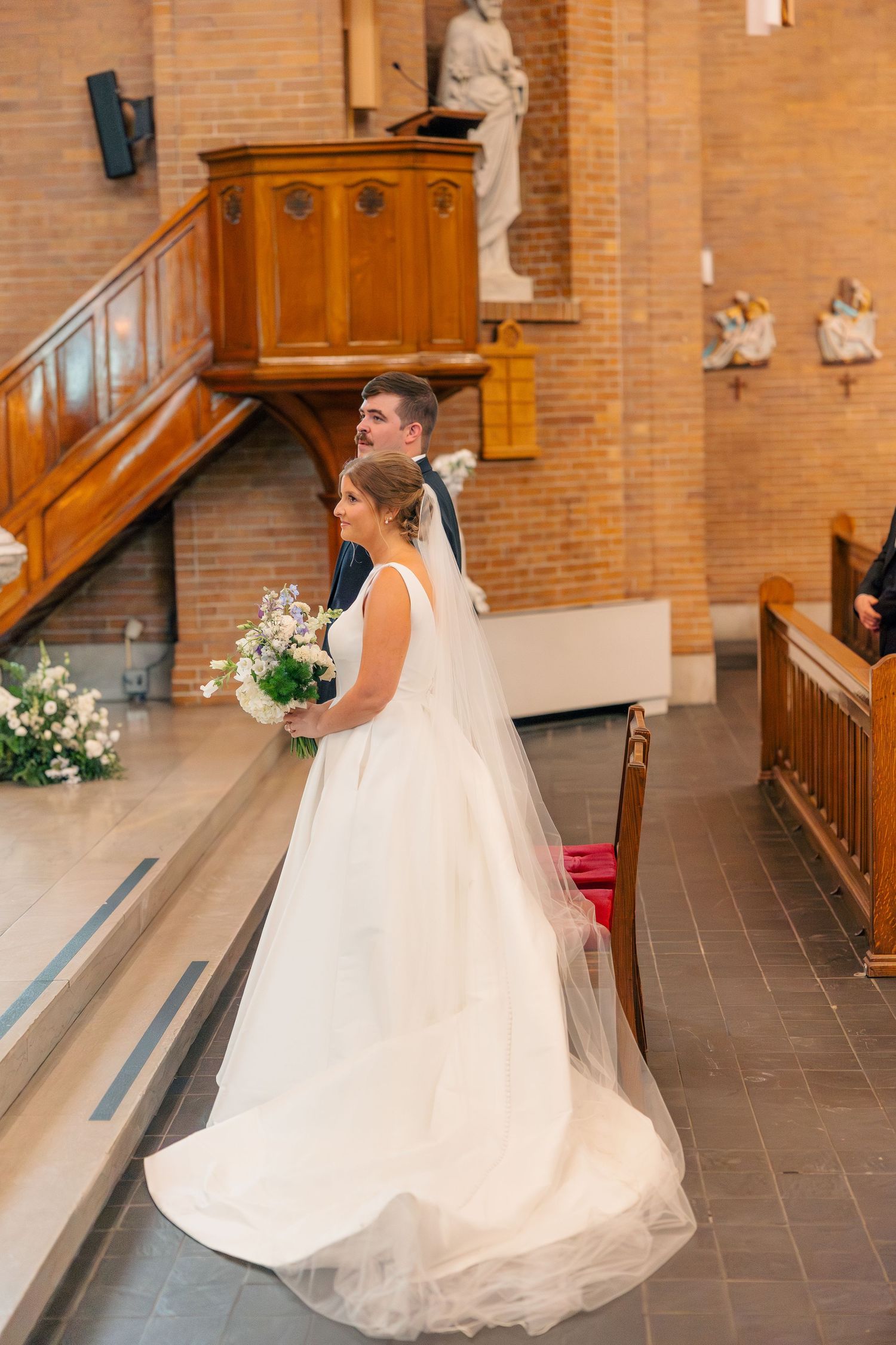 Bride and groom stand together at the altar during their Catholic church wedding ceremony.