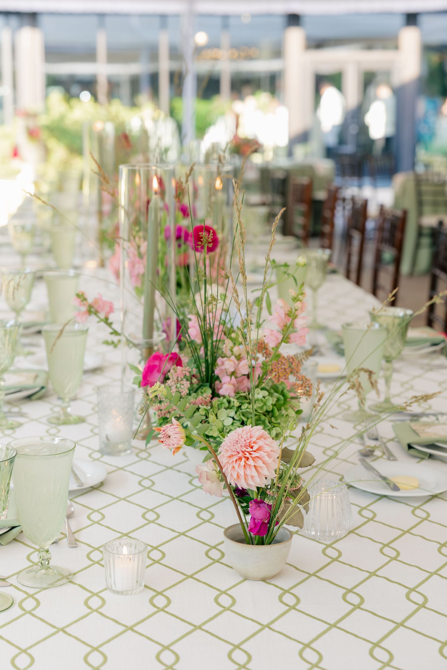 Elegant wedding reception table with pink dahlia and fuchsia floral centerpieces on patterned linen.