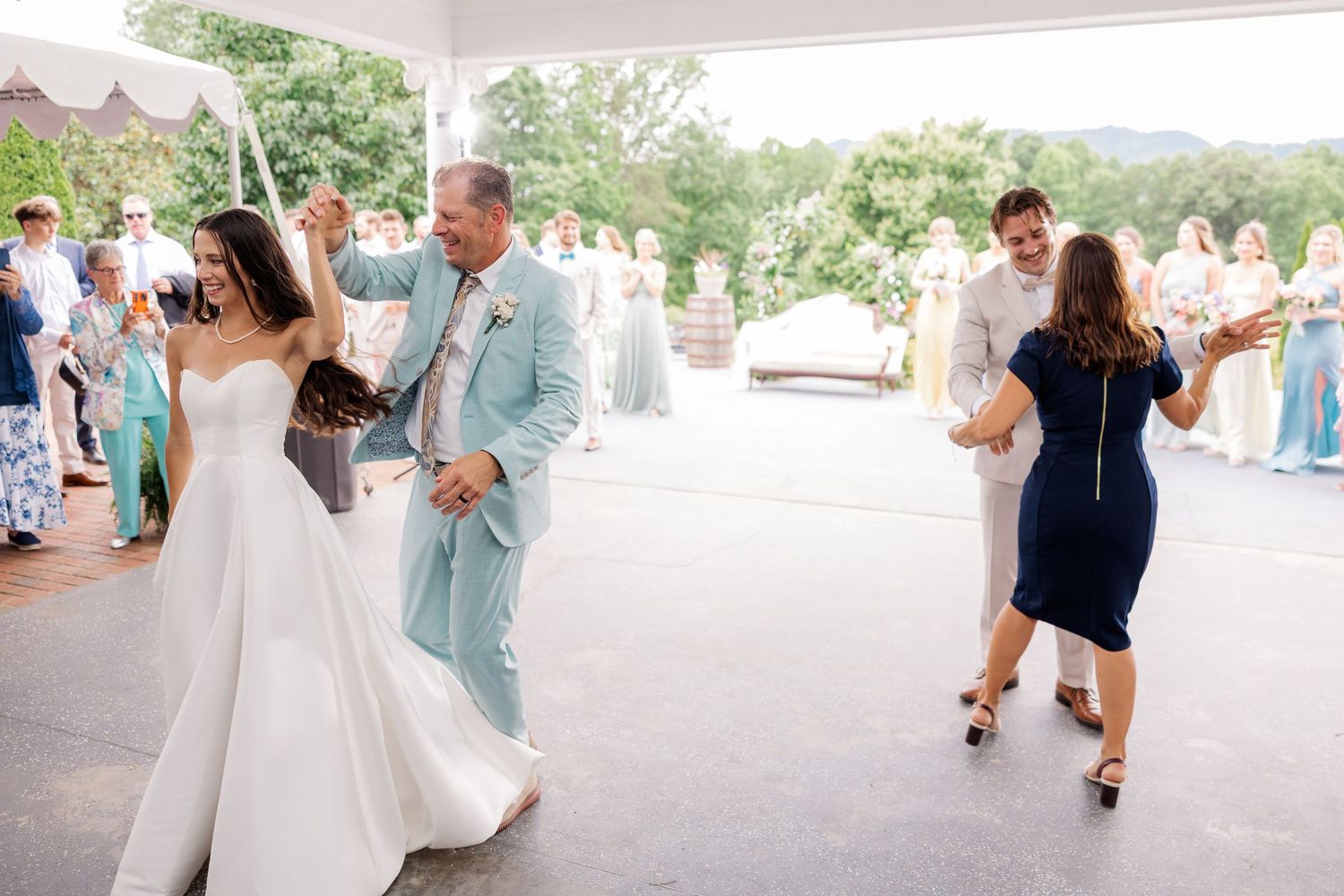 Wedding guests dance and celebrate on an outdoor patio during reception festivities.