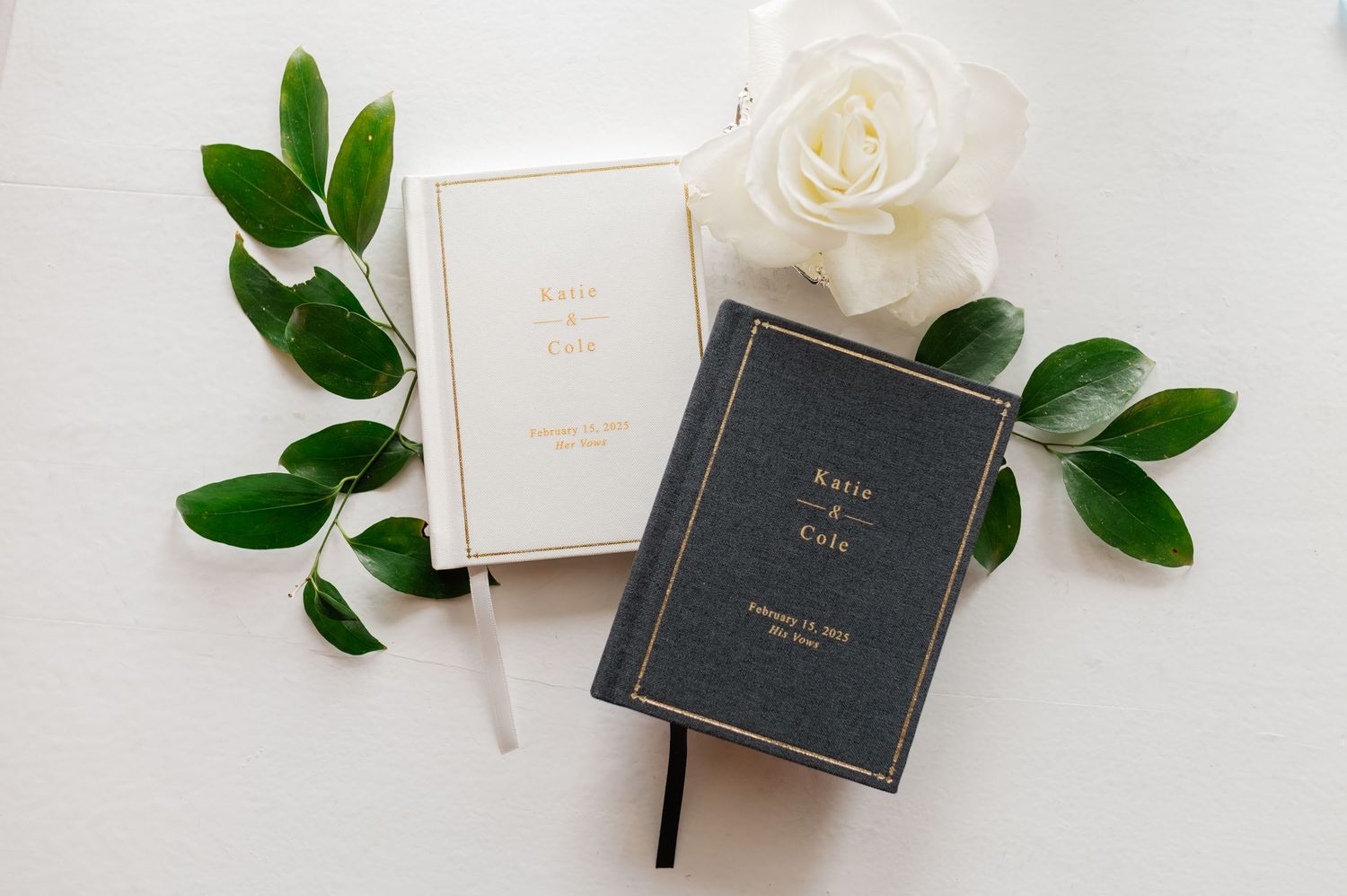 Minimalist wedding details with dark boxes and green foliage on white background.