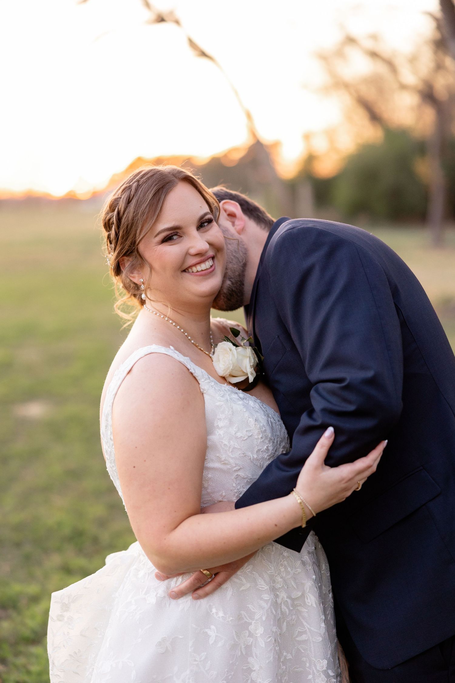 Romantic sunset wedding portrait in a field with couple in formal attire.