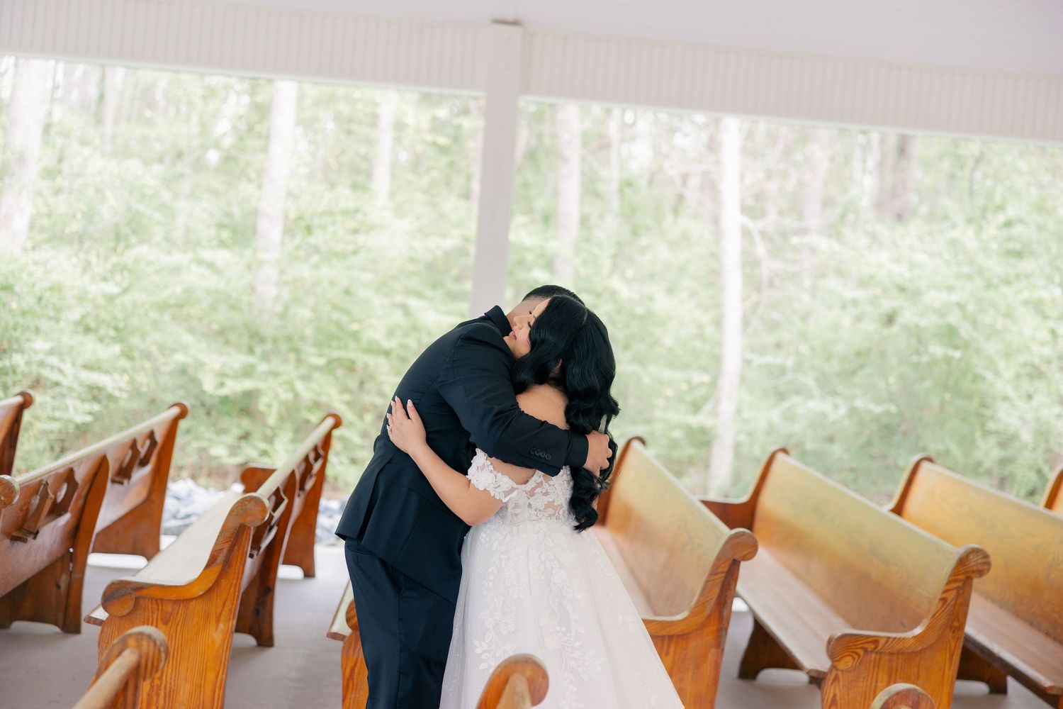Wooden church pews with hydrangea flower decorations lining the aisle for a wedding ceremony.