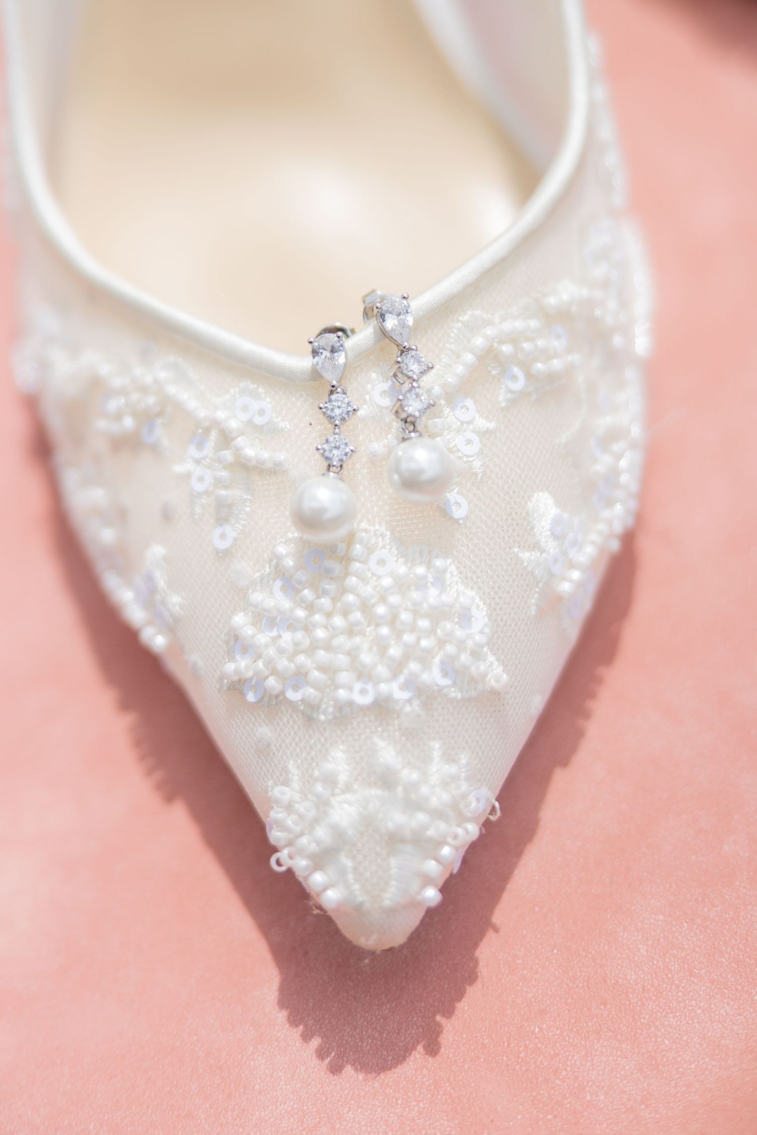 Close-up detail of an ornate white bridal shoe with pearls and crystal embellishments.