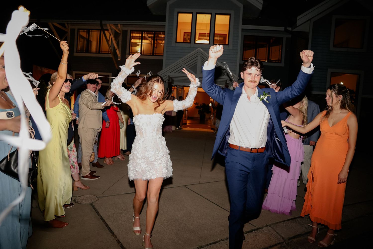 Wedding reception dance floor with guests dancing in evening lighting.