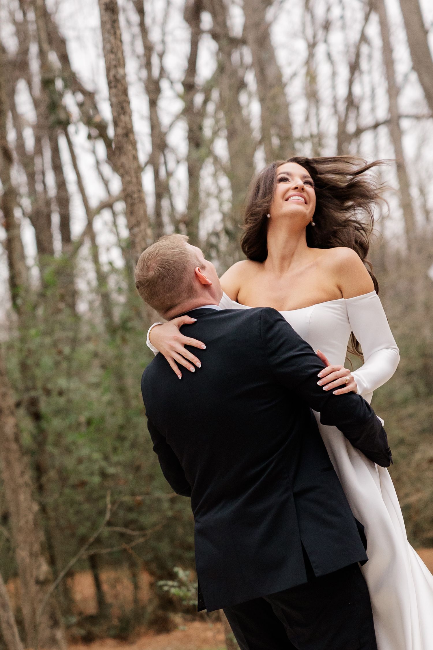 Joyful couple spins and dances together in a romantic wooded setting.