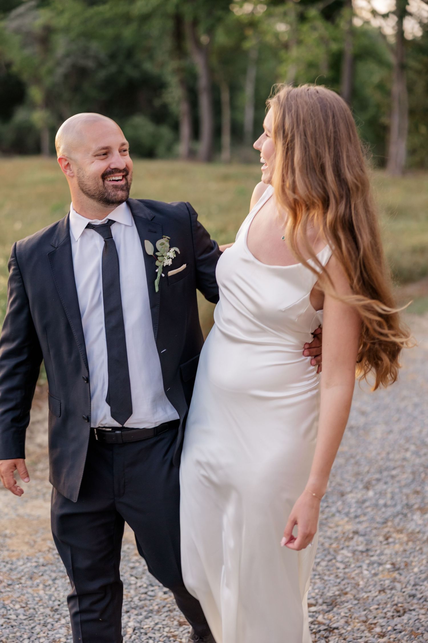 Candid moments of couple laughing and walking together on gravel path.