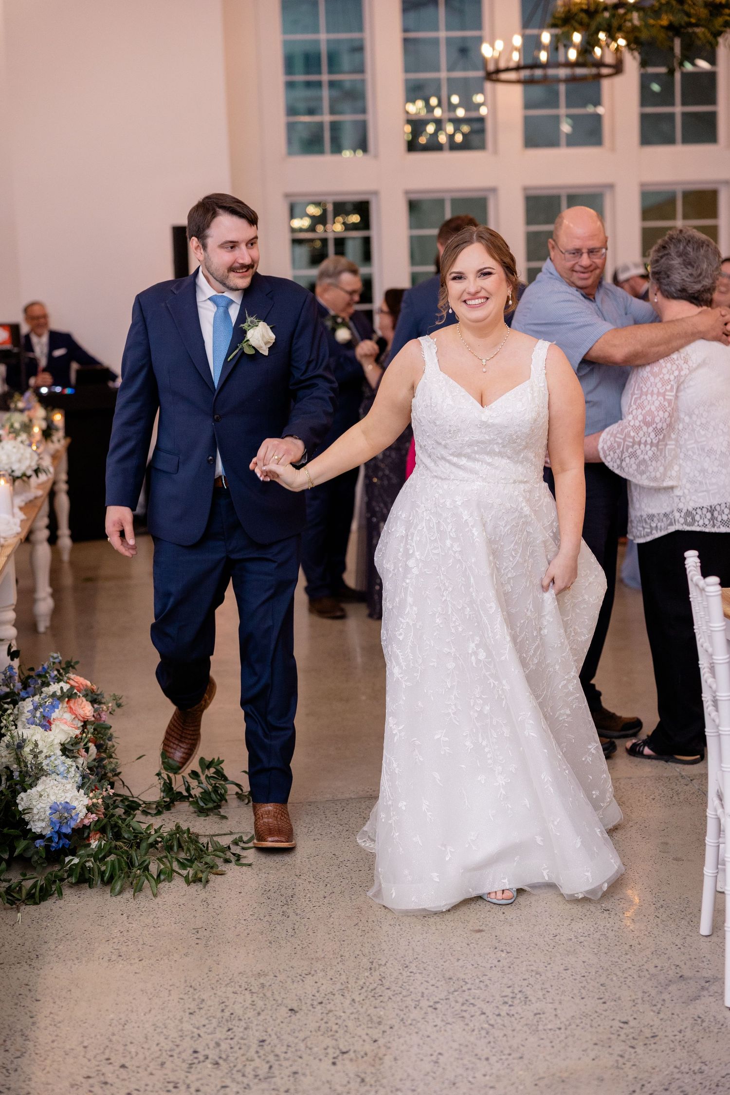 Wedding reception dance floor with guests celebrating in formal attire at an elegant venue with large windows.
