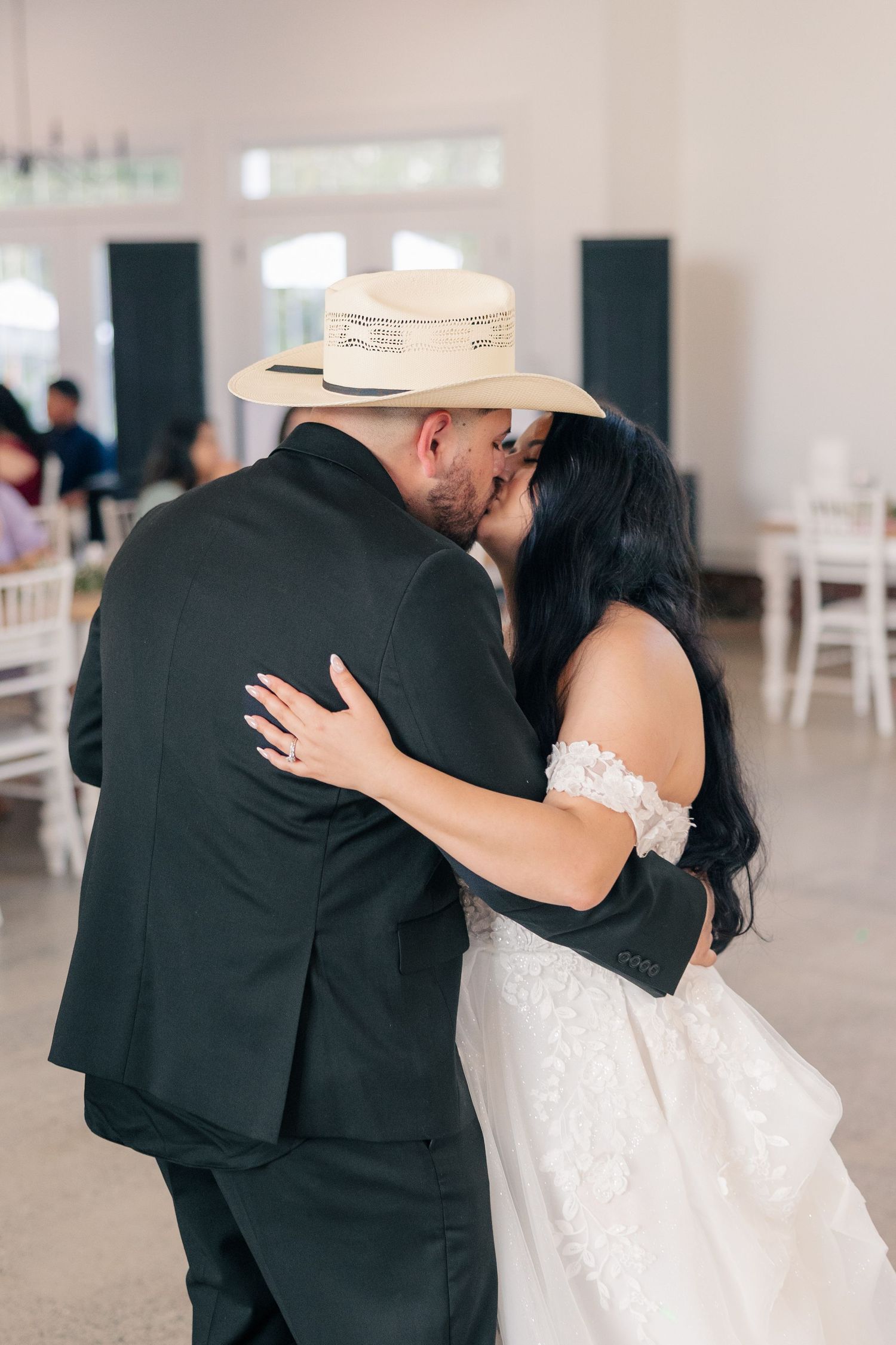 A couple shares their first dance in an elegant white indoor venue.