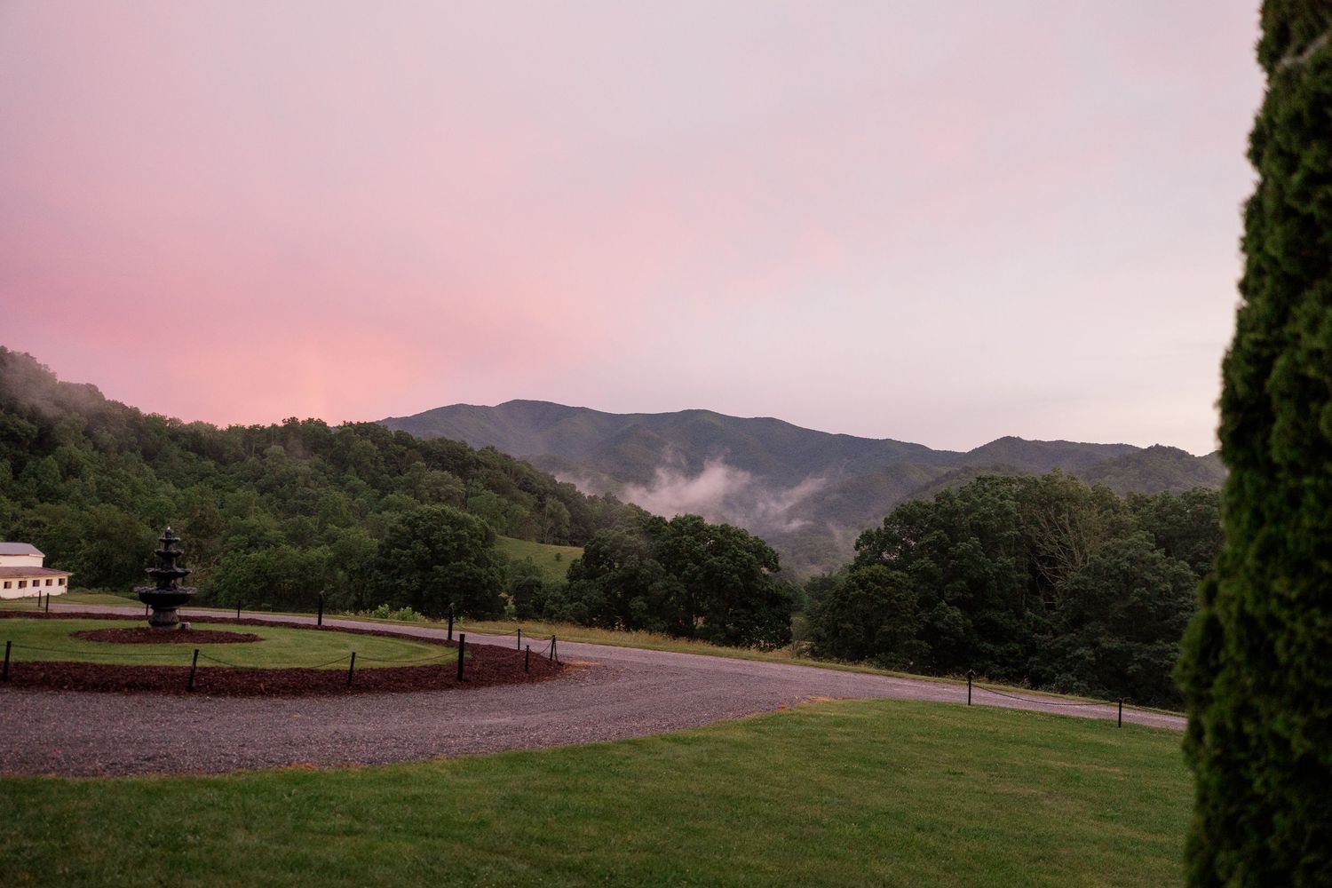 Sunset view of mountains and rolling hills with pink and purple sky.