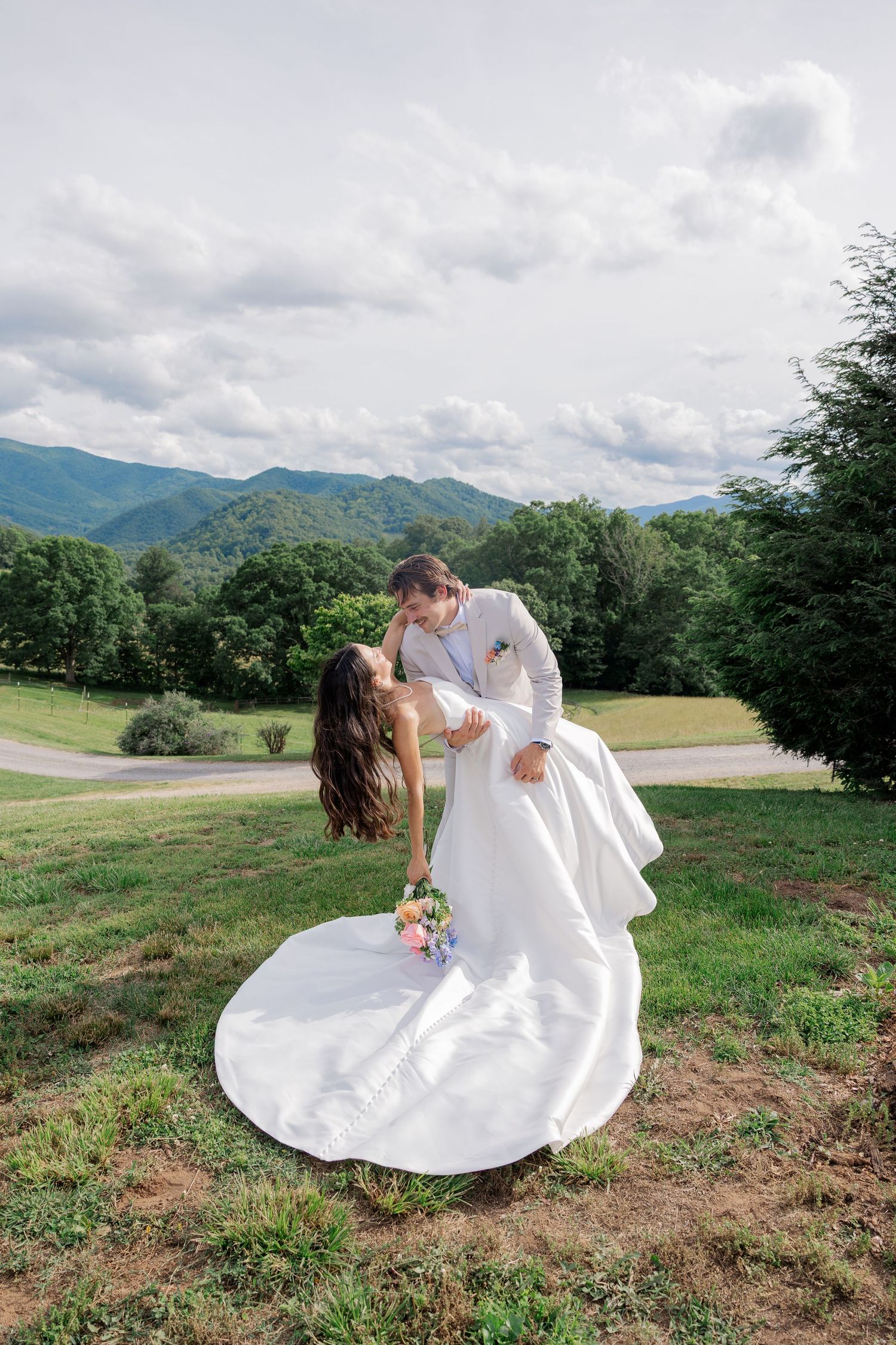 Wedding couple sharing romantic moment against mountain landscape backdrop.