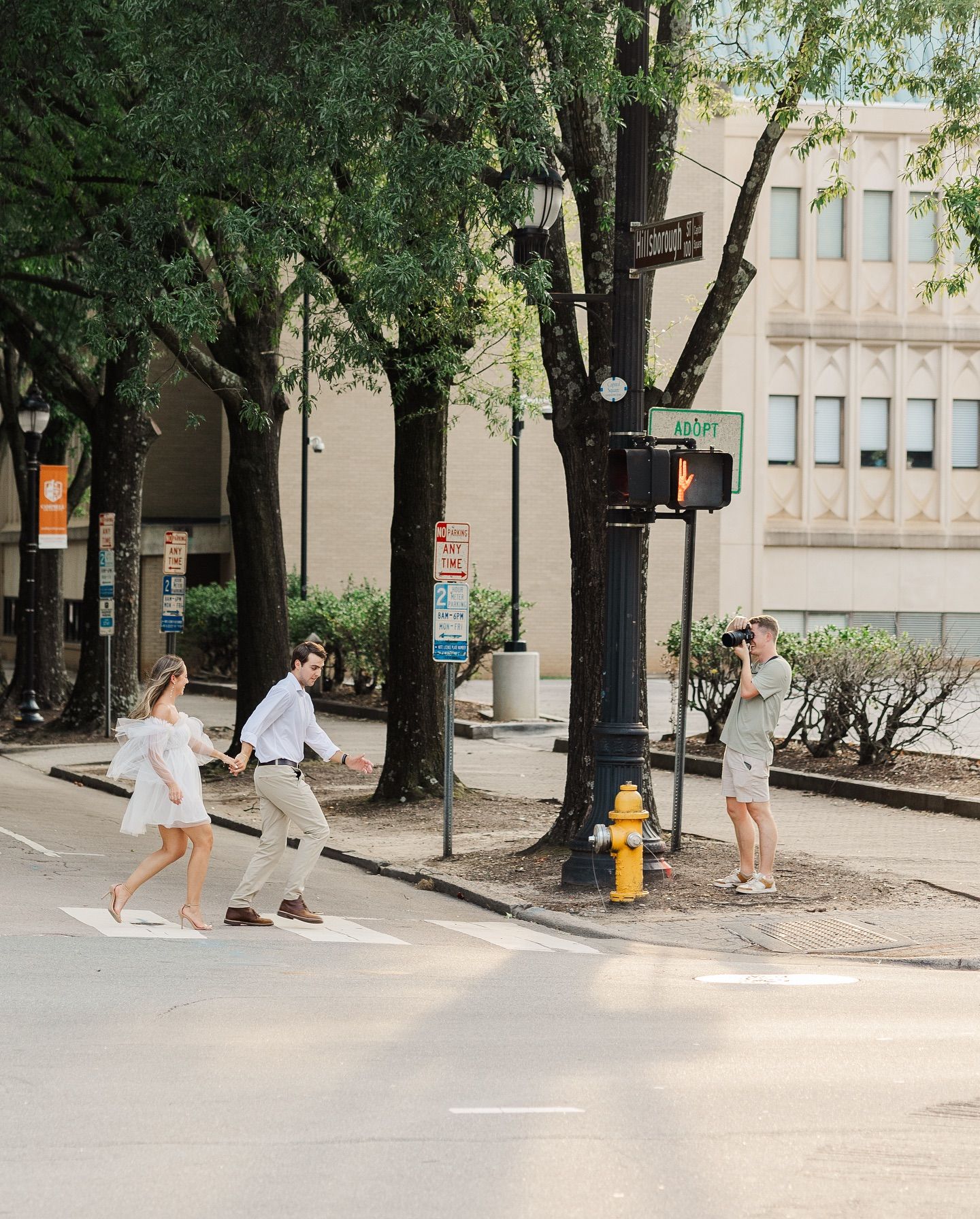 Wedding photo shoot on an urban street corner with trees and city buildings.