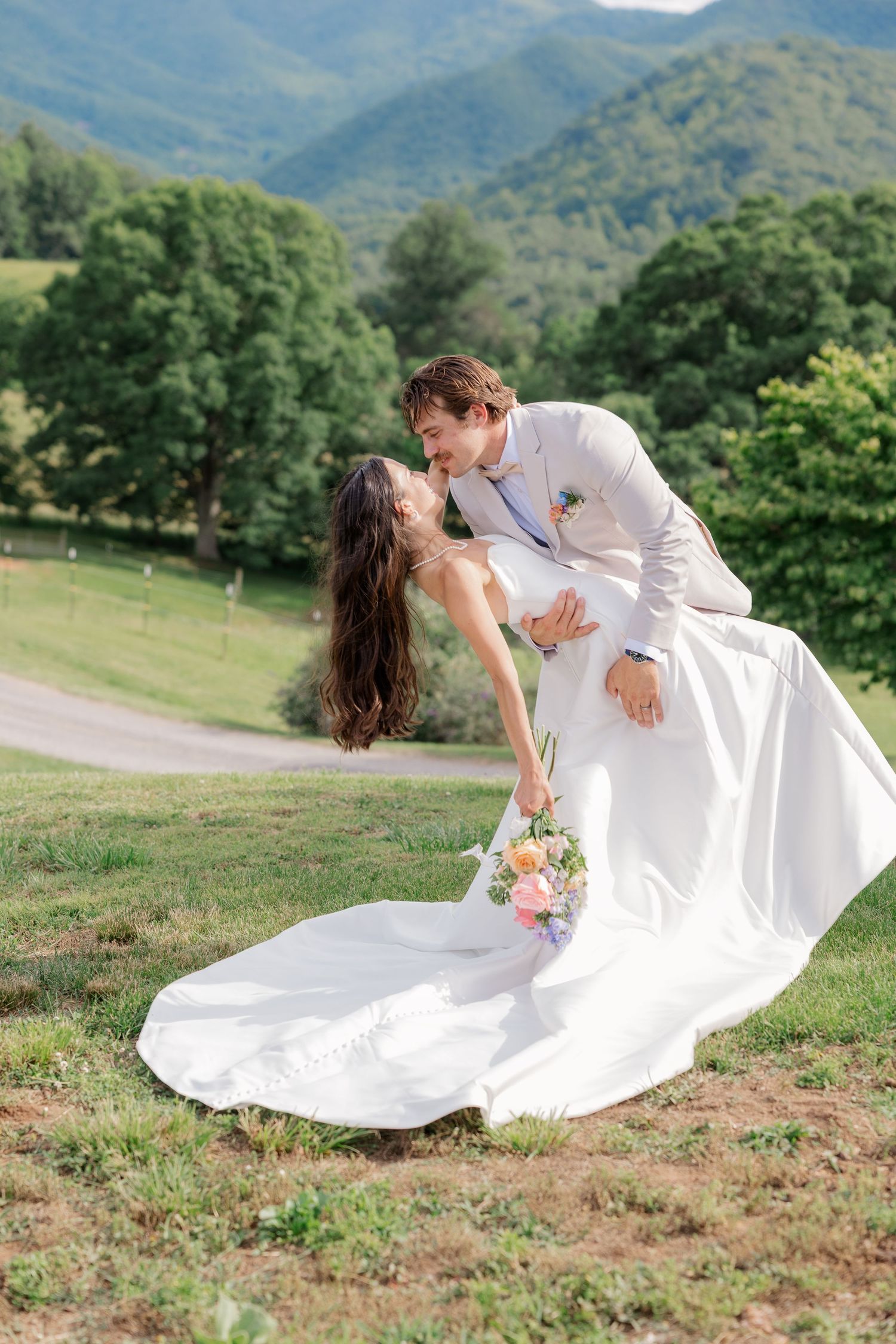 Romantic wedding photo shoot with couple in white against scenic mountain landscape.