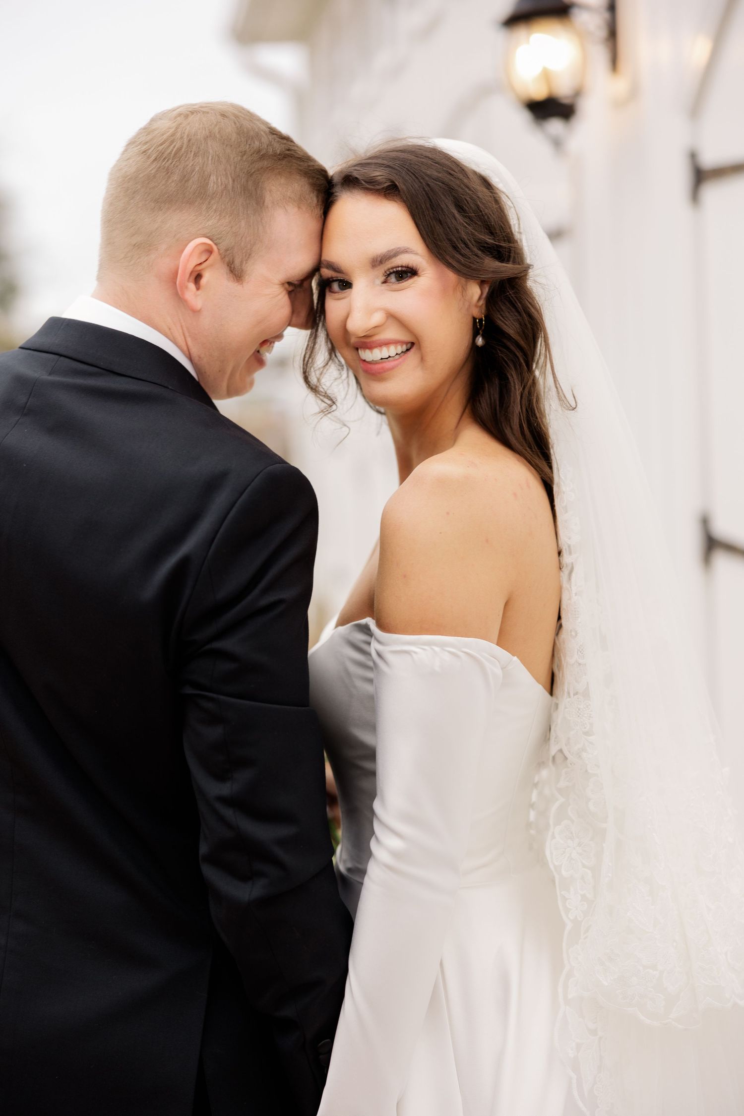 Intimate wedding portrait against white wall with lantern.