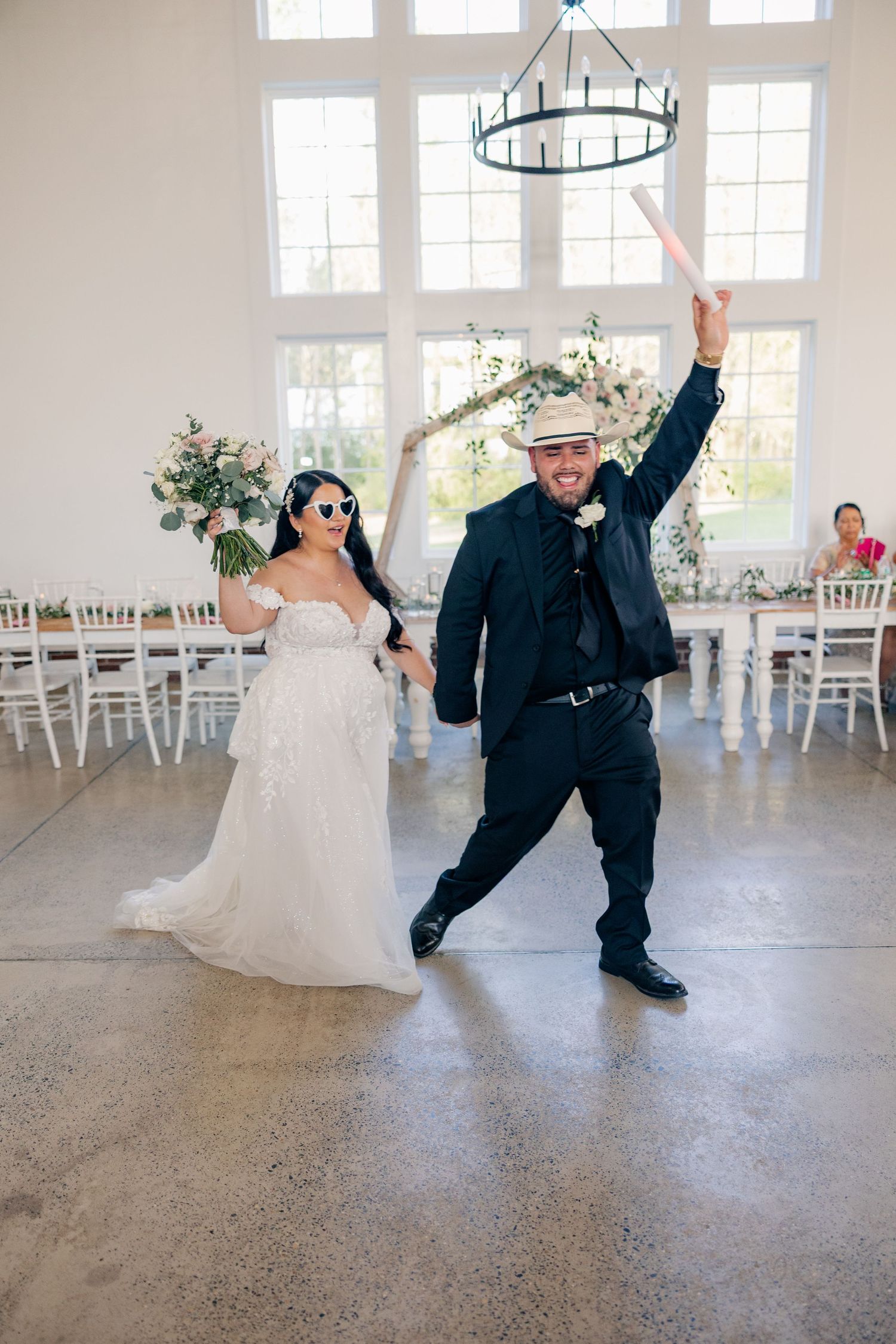 Fun and playful dance moves by newlyweds in a bright, modern reception venue.