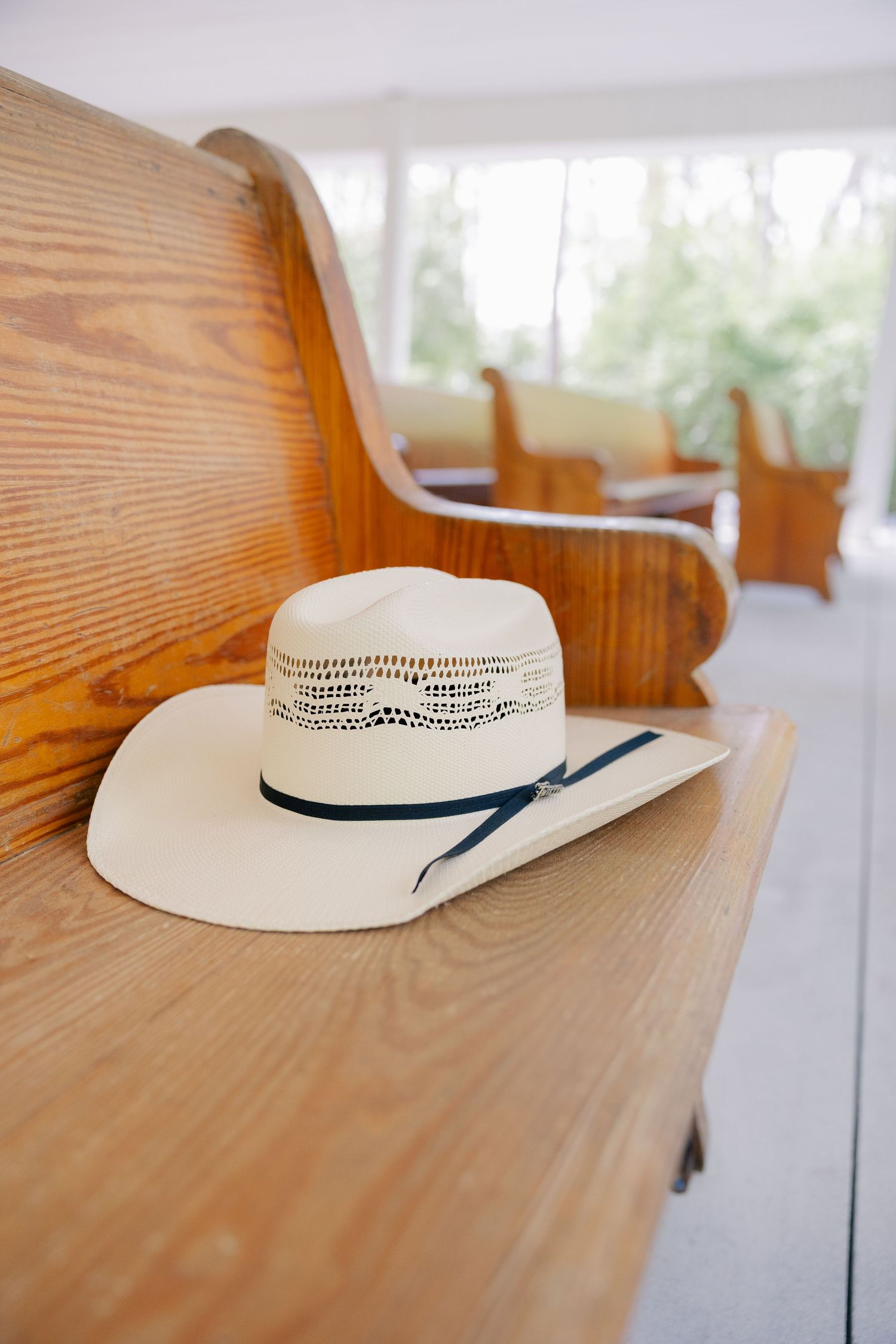 A cream-colored straw hat with navy ribbon trim resting on a wooden table.