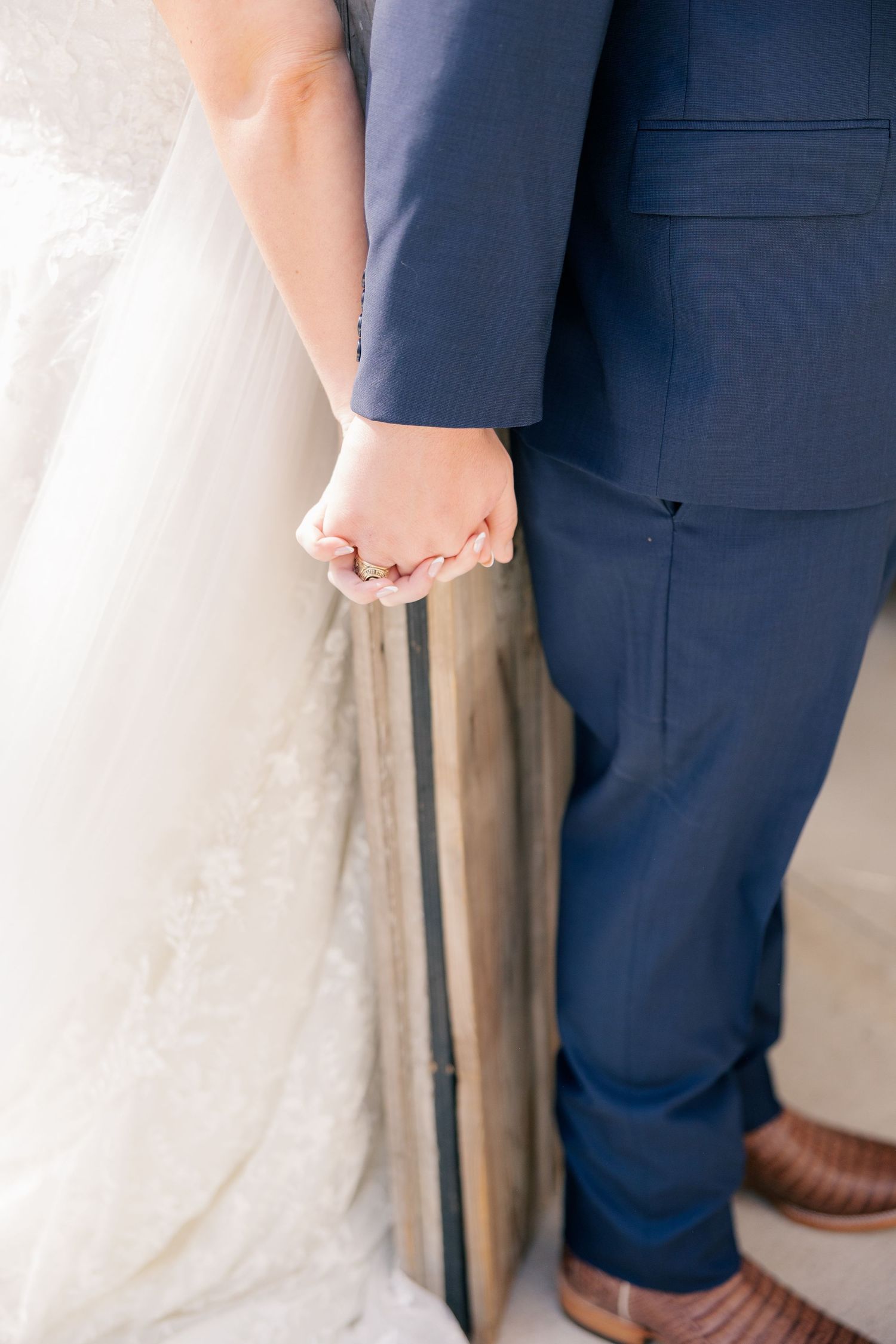 Close-up details of wedding attire showing navy suit next to white bridal gown.