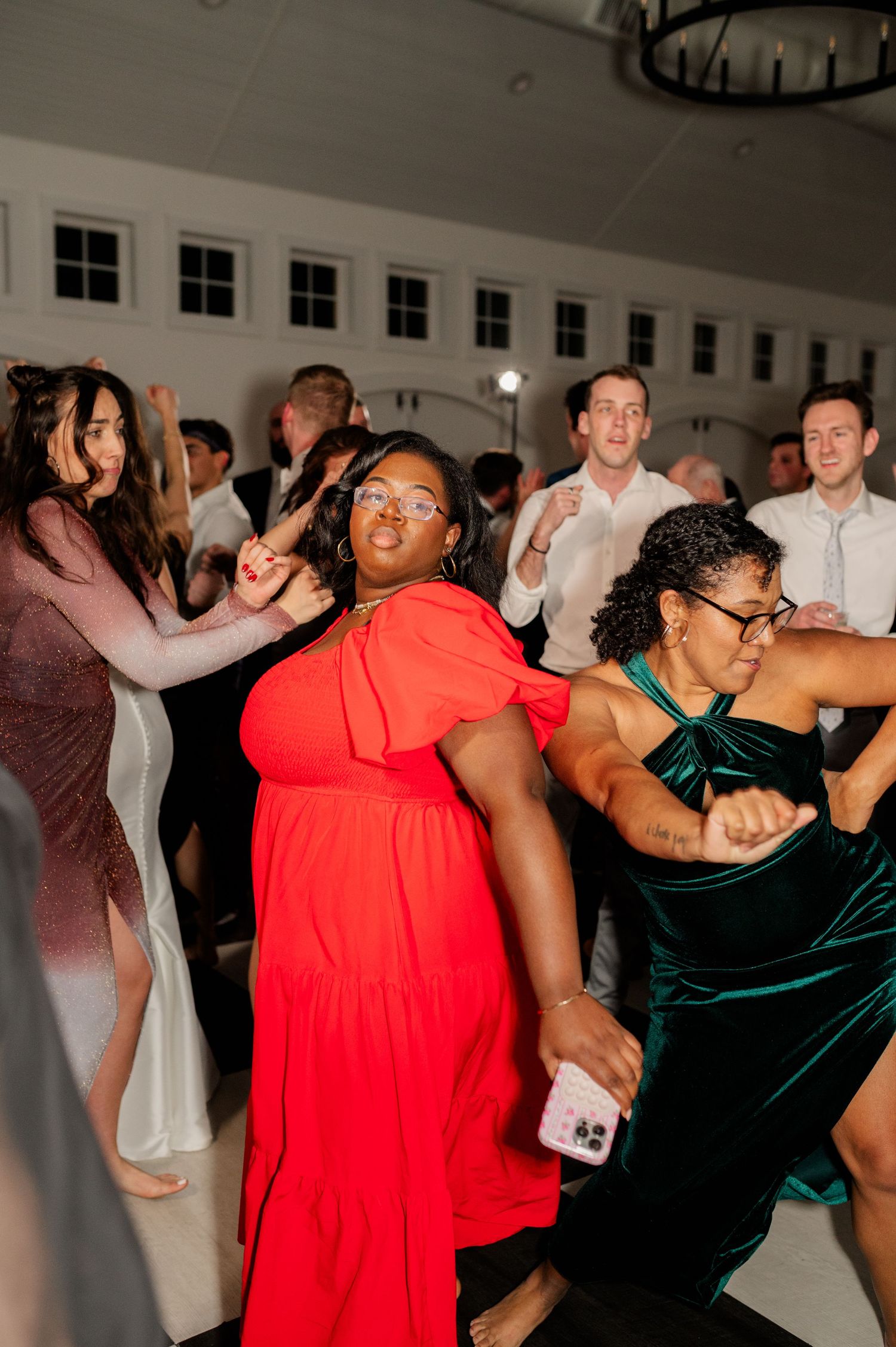 Wedding reception guests dancing energetically in formal attire under chandelier lighting.
