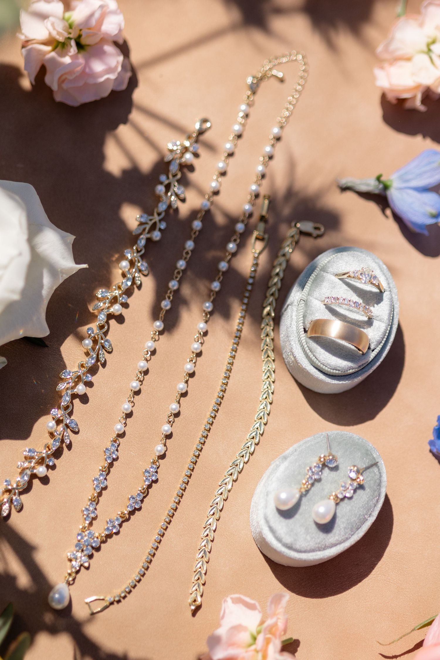 Delicate crystal and pearl bridal jewelry displayed on a peach-colored surface in natural lighting.