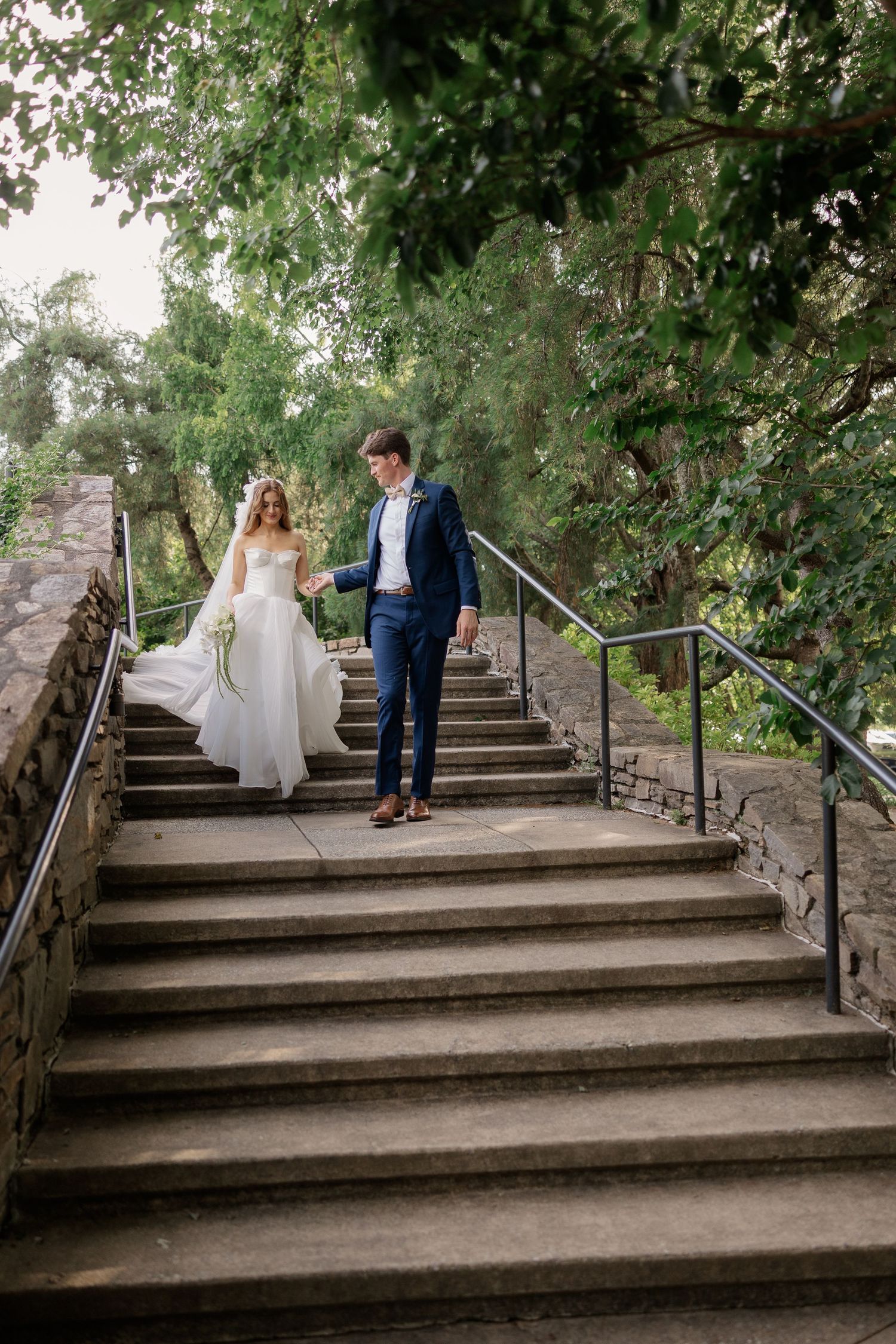 A couple descends stone steps together during their wedding photoshoot.