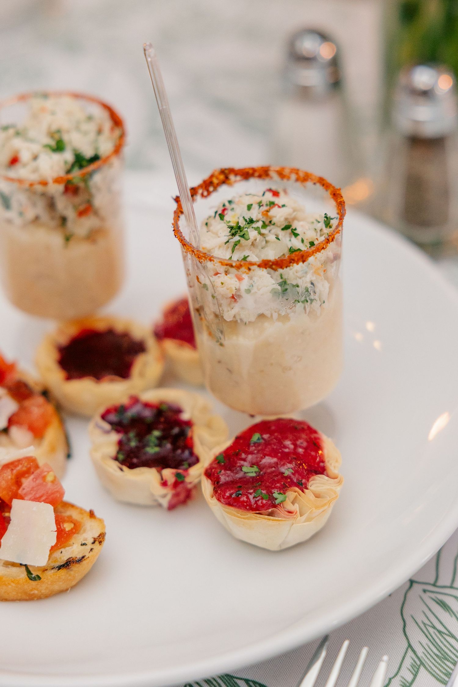 Elegant wedding reception appetizers including savory tartlets and creamy dip shots on white plate.