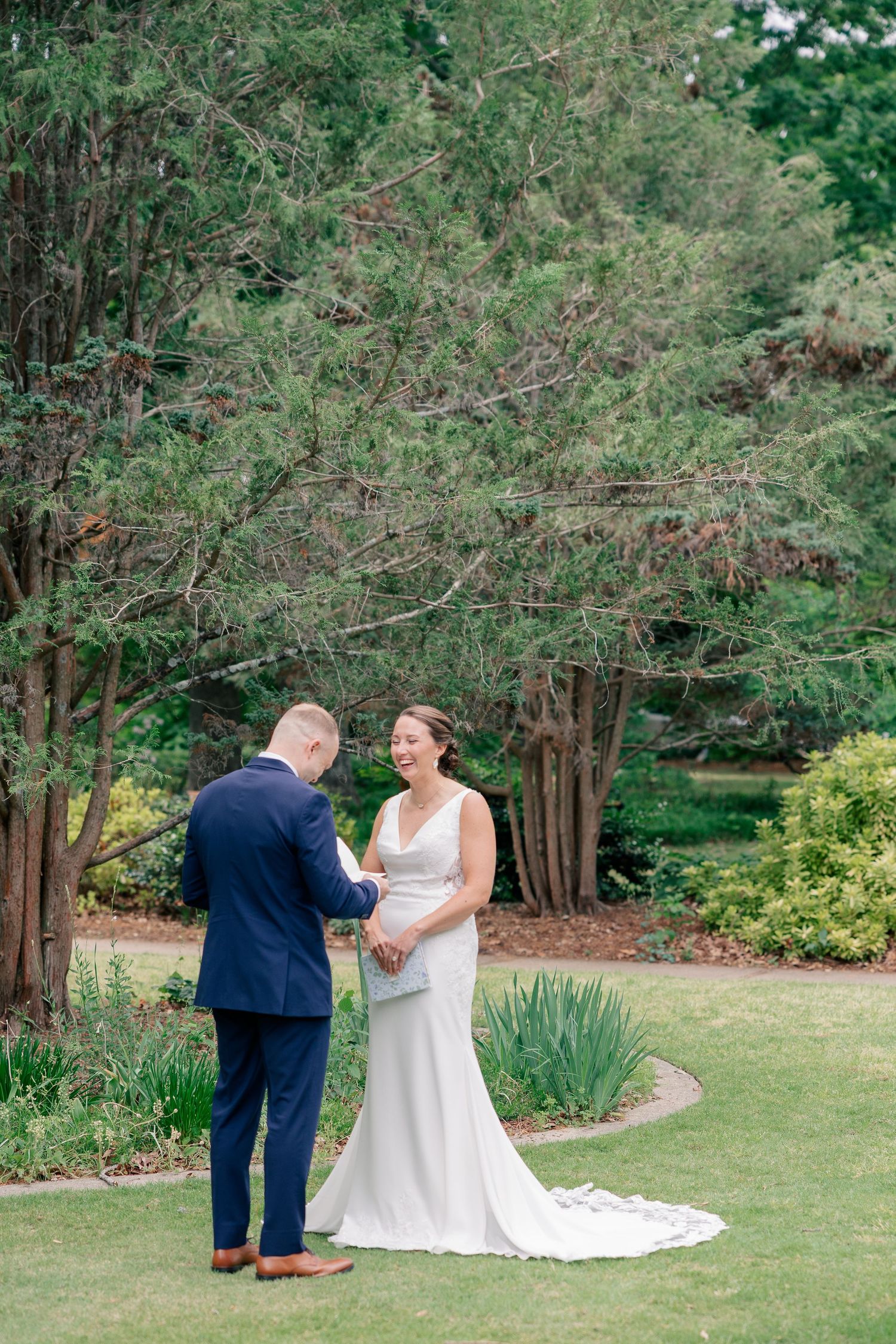 Bride and groom share a tender first look moment in a lush garden setting during their outdoor wedding ceremony.