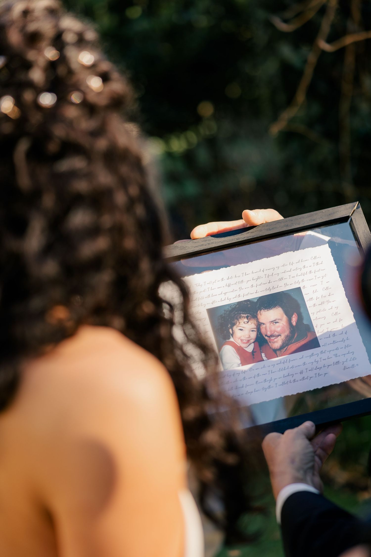 Close-up shot of someone holding a sentimental photo album during an outdoor event.