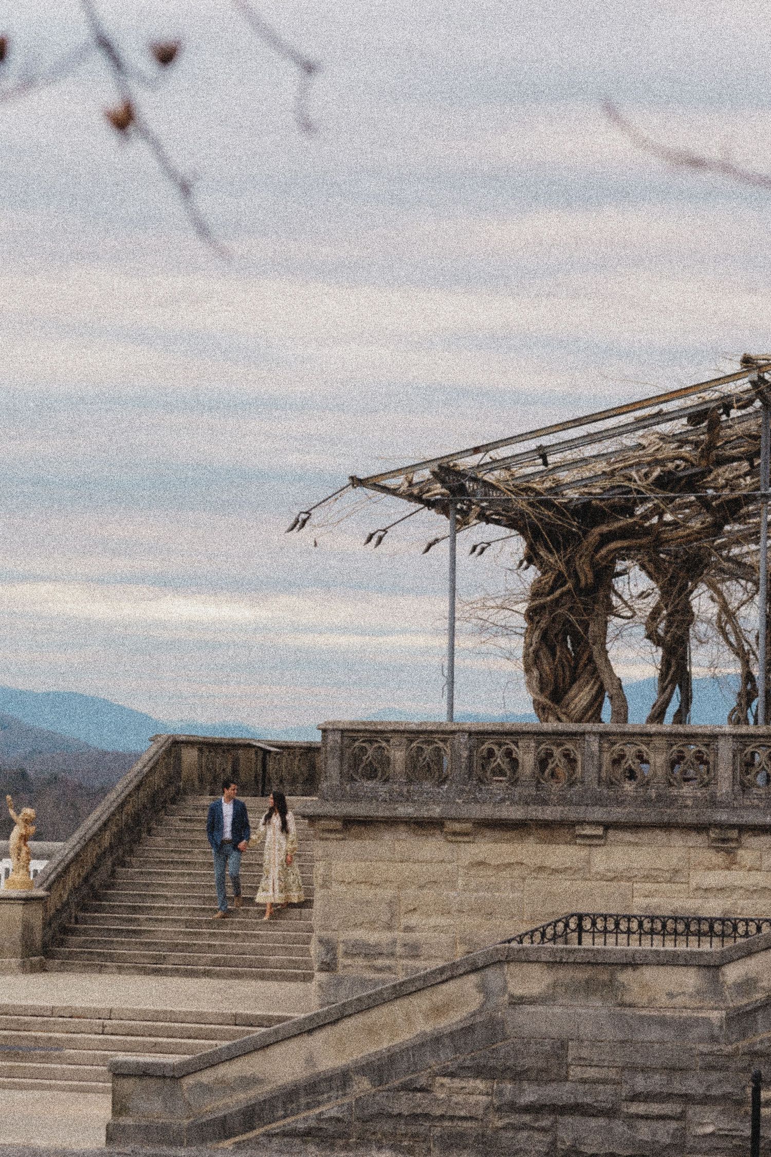 Stone terrace with mountain views featuring ornate architecture and a weathered pergola structure.