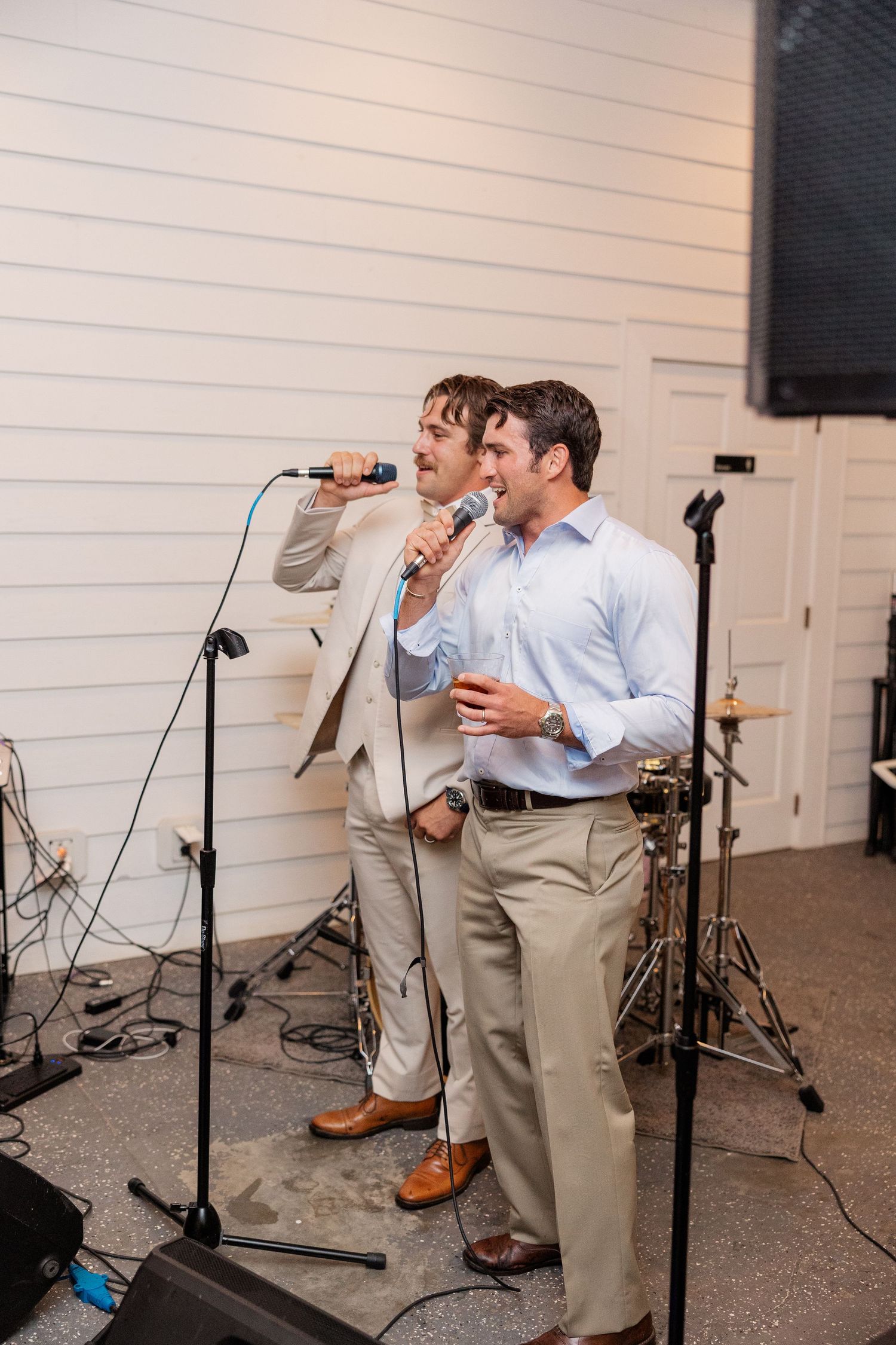 Wedding reception performers singing into microphones on stage.