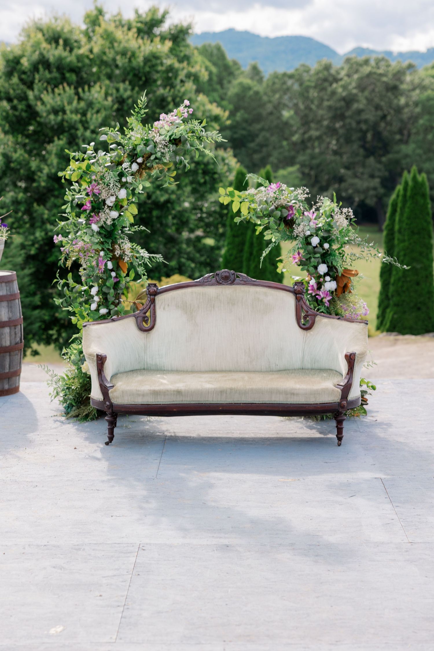 A vintage floral-adorned settee sits outdoors with mountain views.