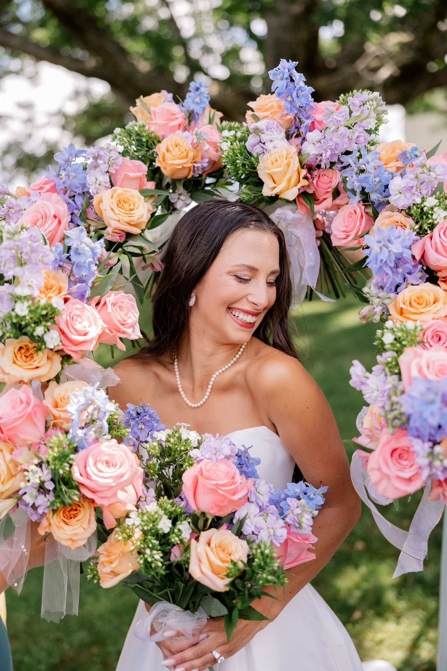 Romantic wedding bouquet featuring pink roses and purple delphiniums arranged in an elegant cascade style.