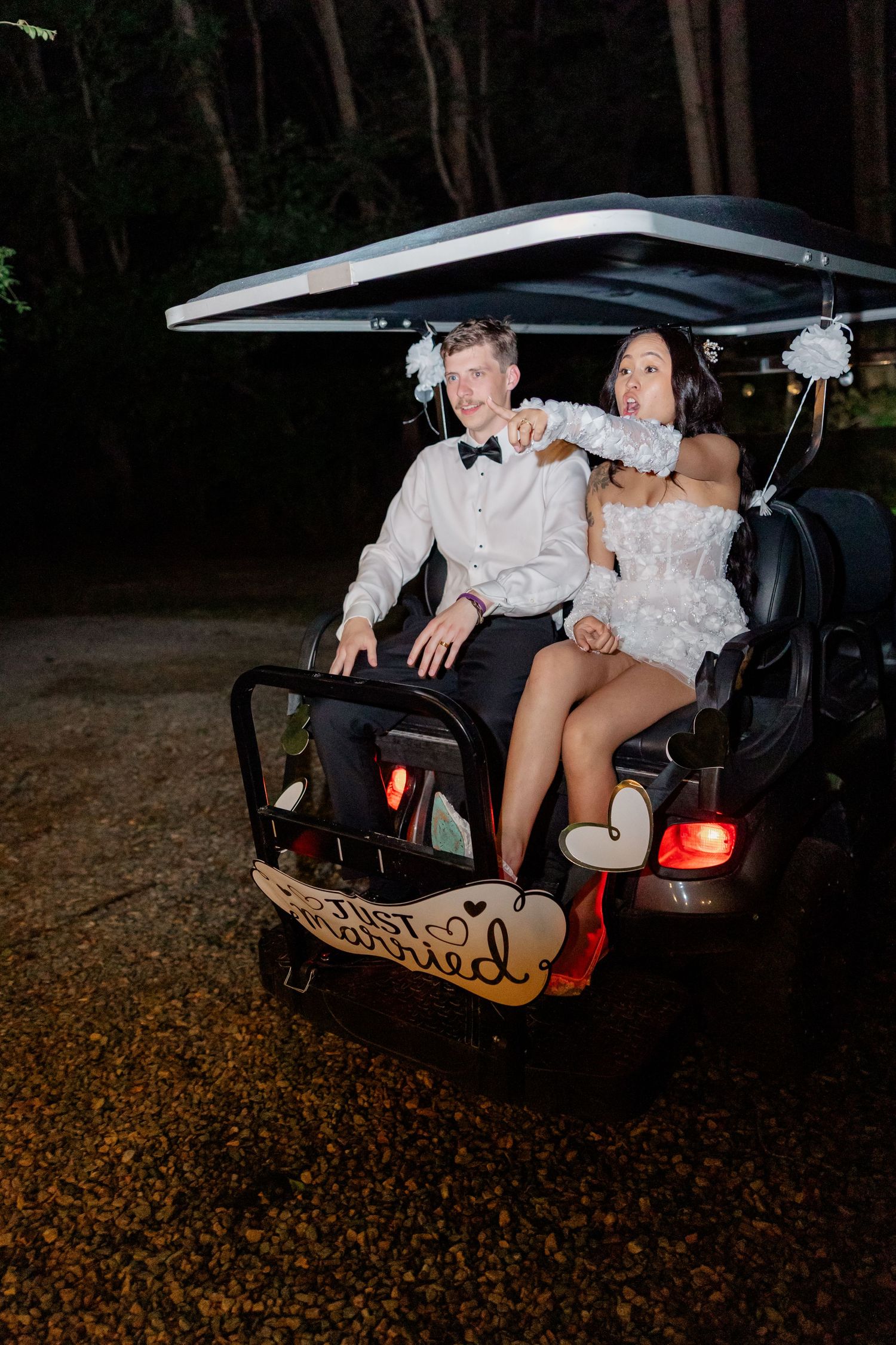 Couple sitting in the back of a decorated car during evening celebrations.