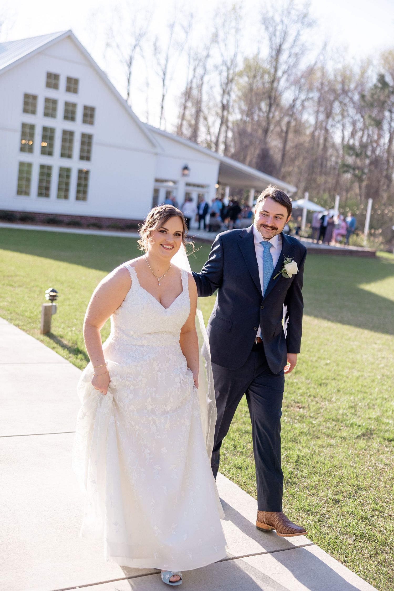 Wedding party walking outside a white church building on a sunny day.