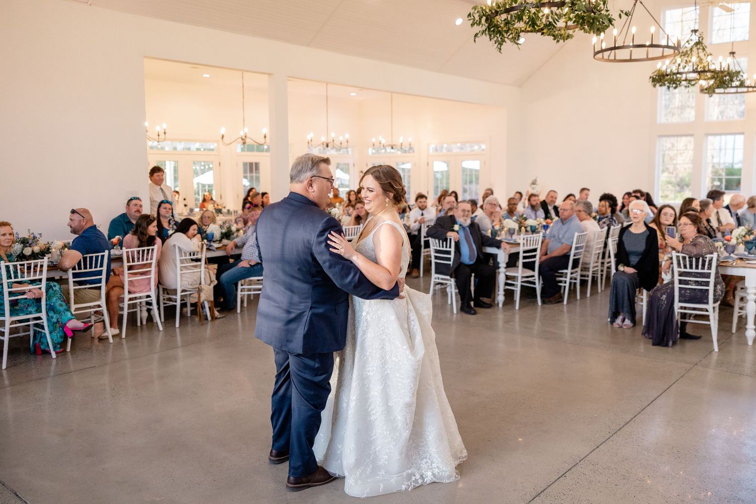 Wedding reception venue with white decor and chiavari chairs set up for guests.