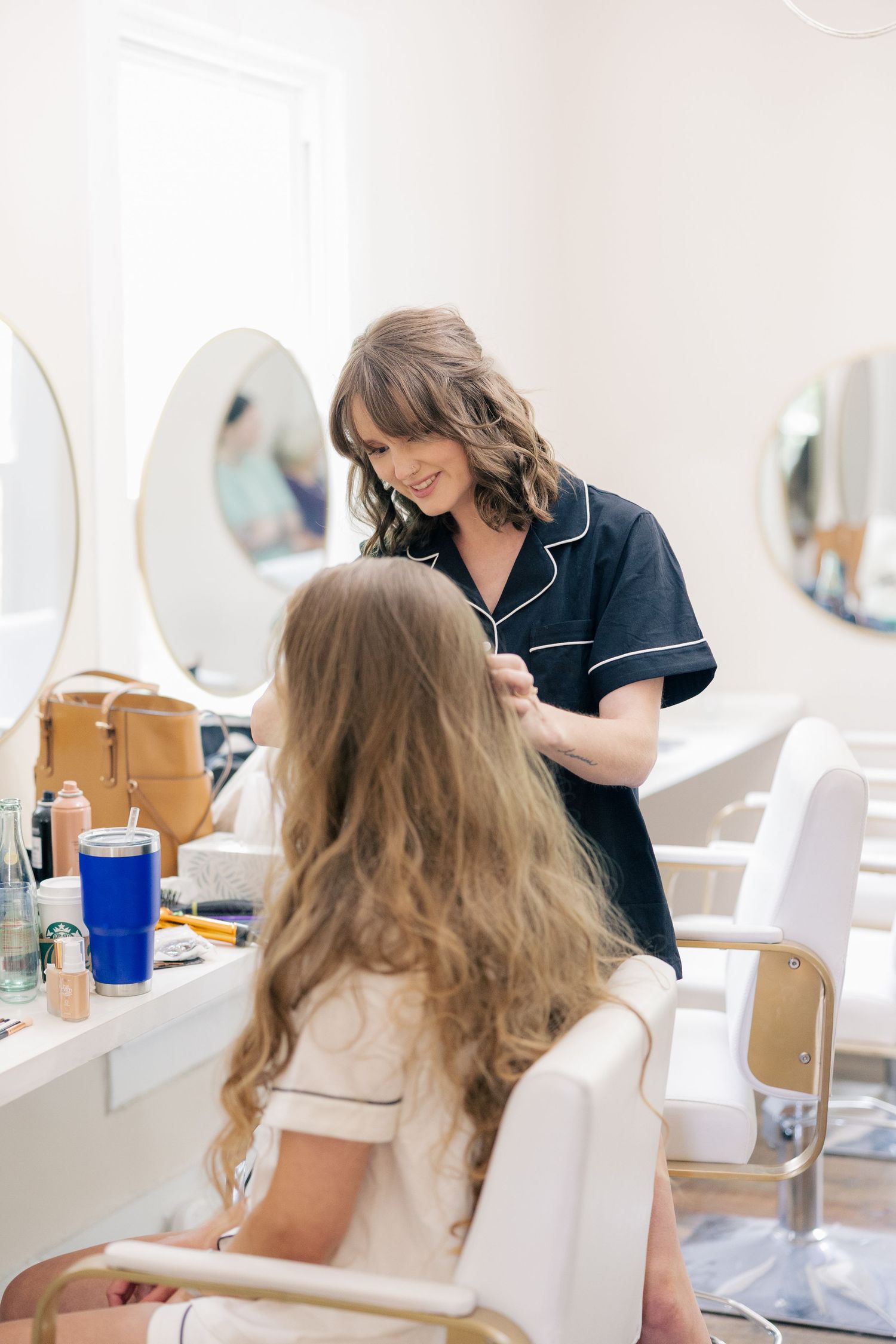 Styling session in a bright white room with mirrors and vanity stations.