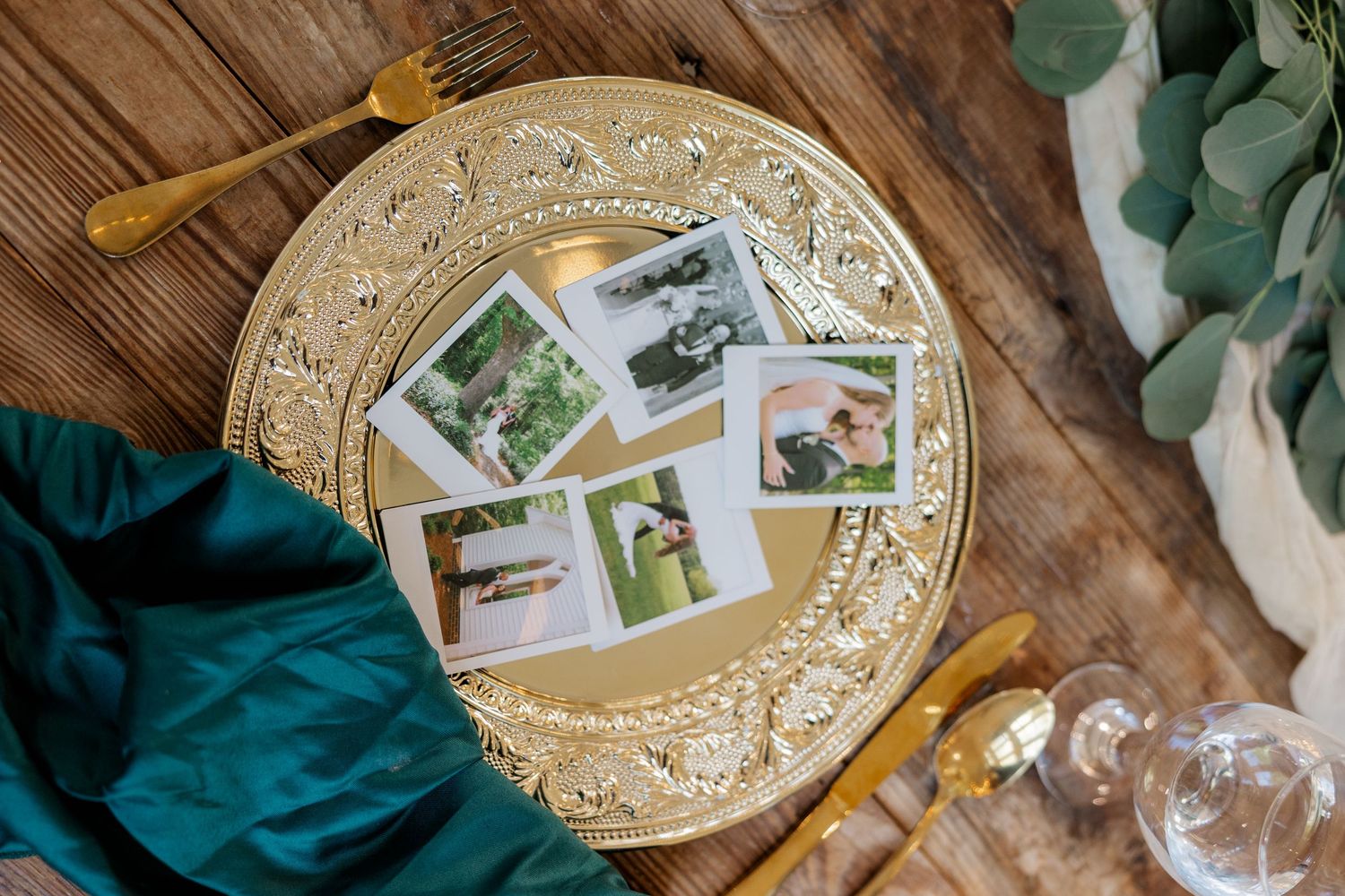 Wedding photos displayed on an ornate gold plate with eucalyptus and teal fabric accents.