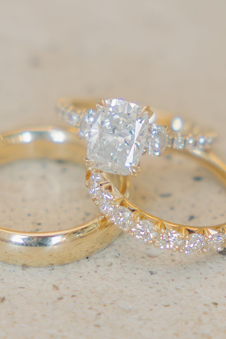Gold wedding ring set featuring cushion cut diamond engagement ring with diamond band and plain gold band.