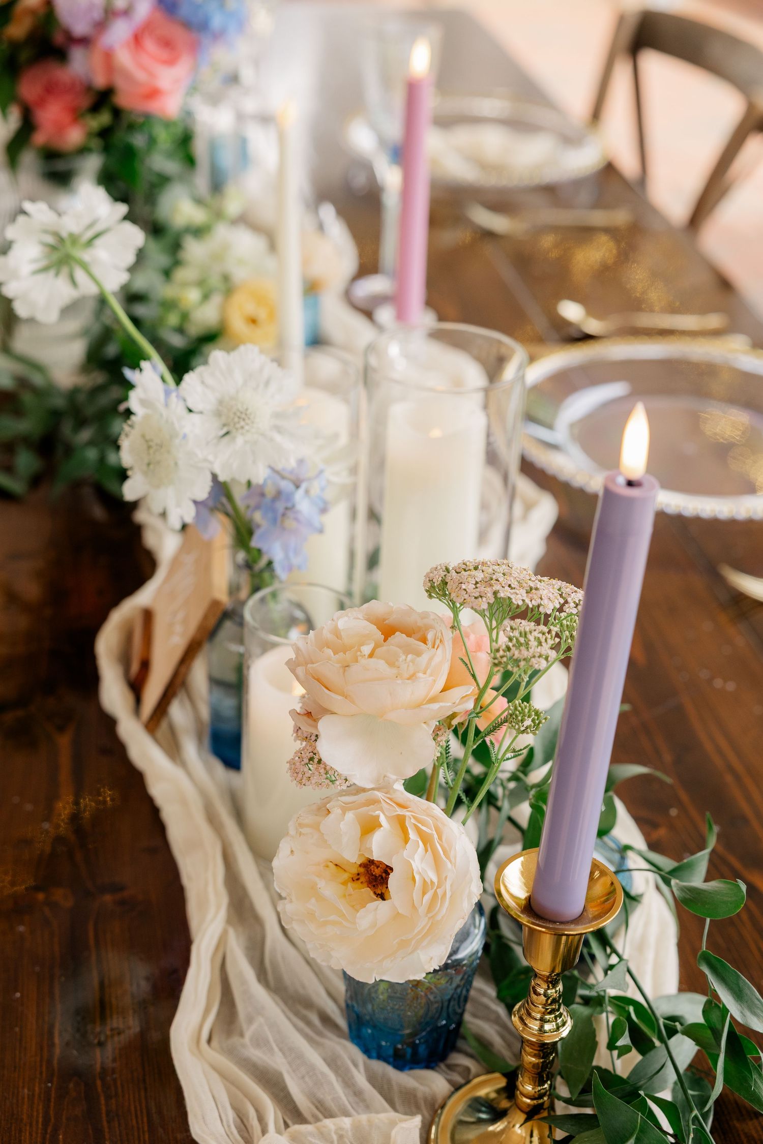 Elegant table setting with pastel flowers, lavender candles, and white table runner.