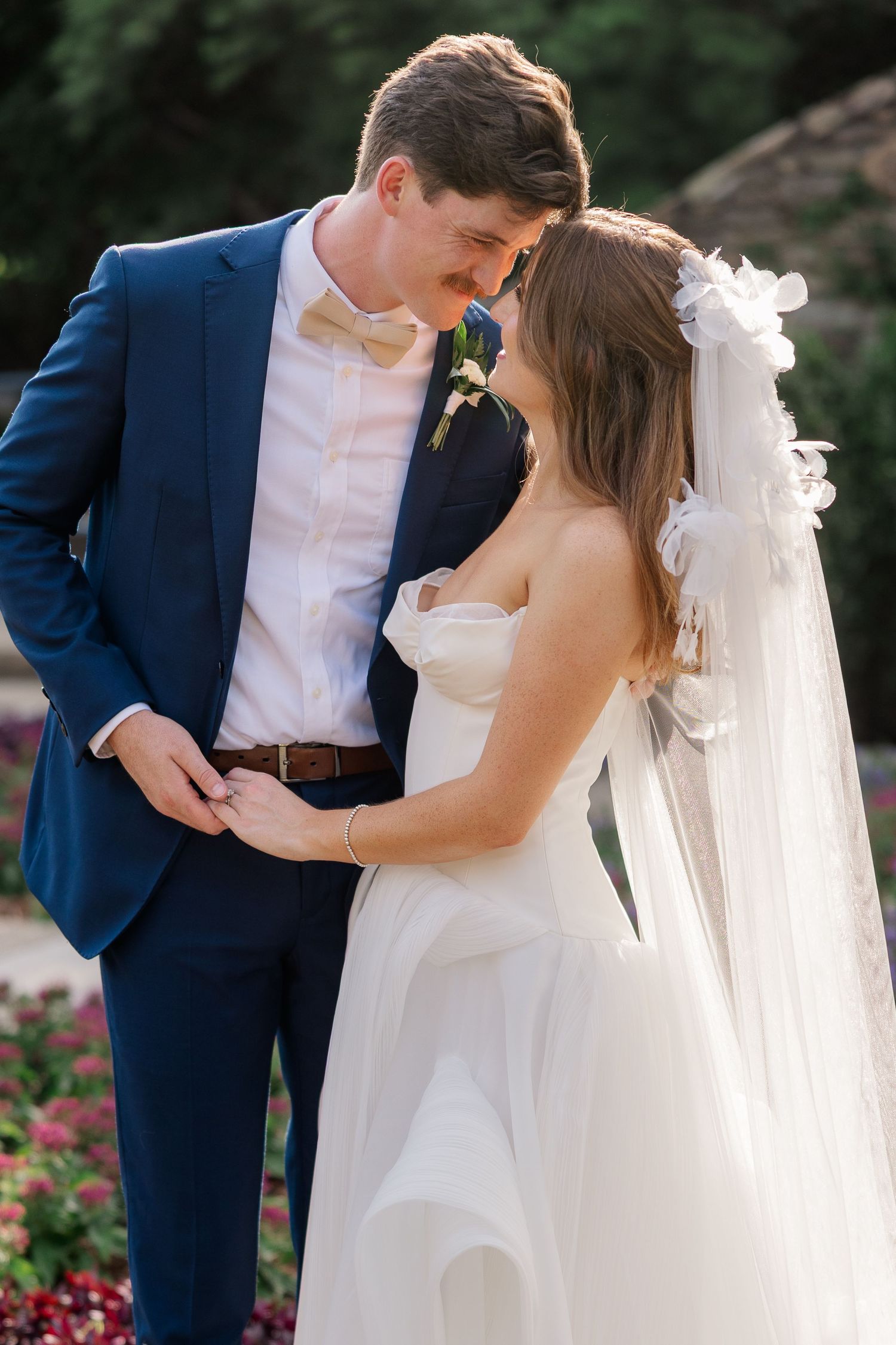Romantic wedding portrait in a garden with flowing white veil.