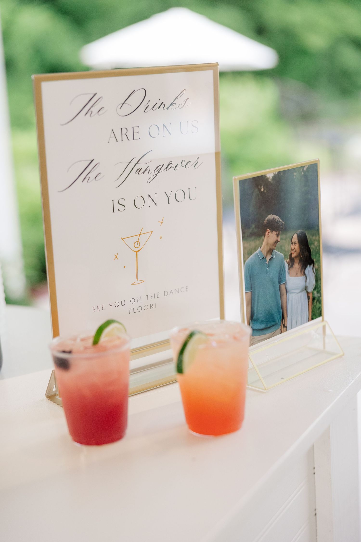 Wedding drink sign and cocktails display with sunset ombre beverages.